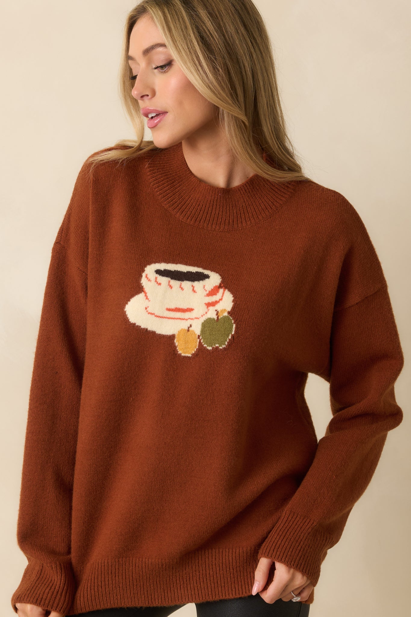 A cropped close-up showing knit texture and detailed design of the coffee cup and apple.