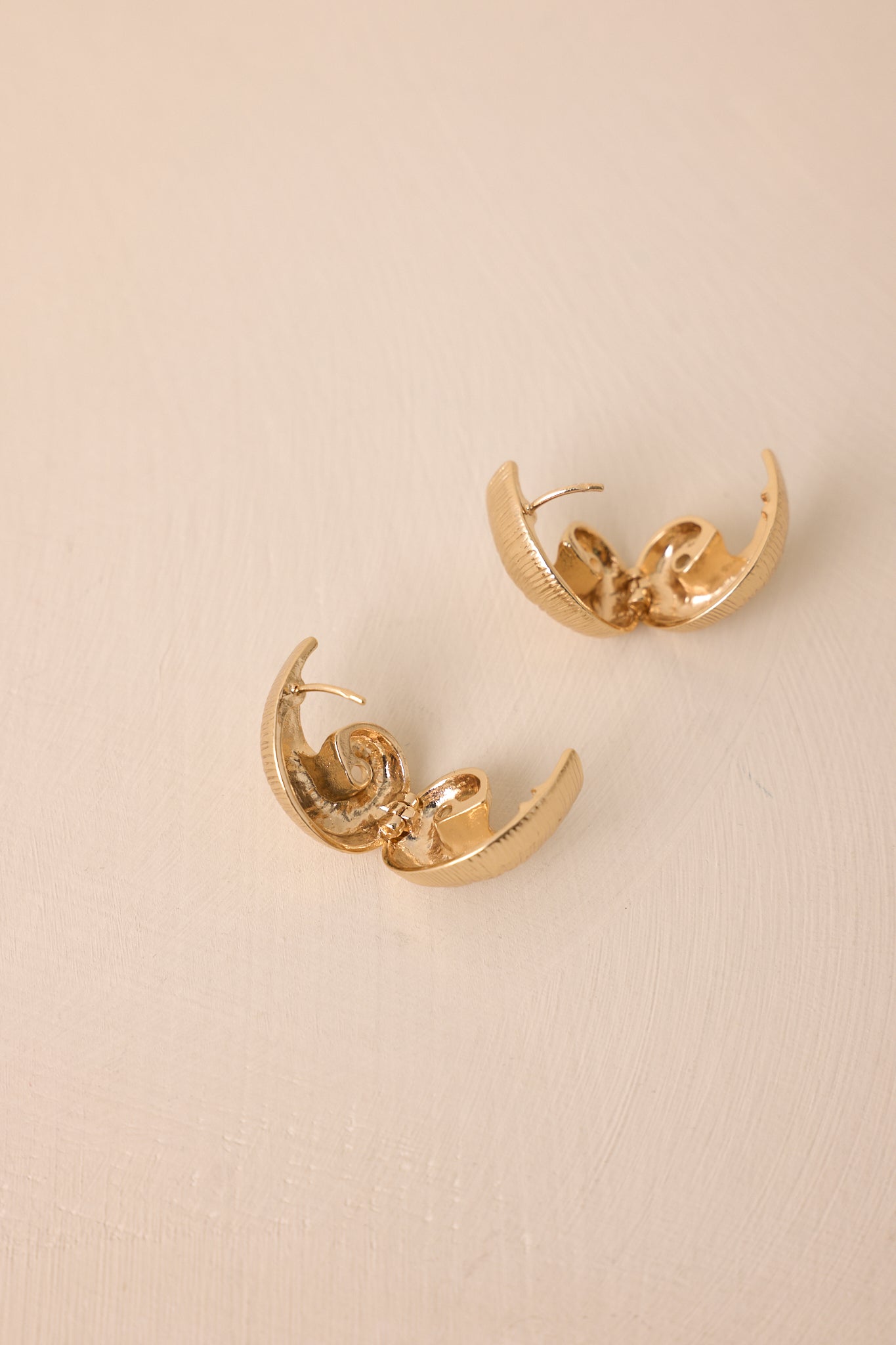 A cropped close view showing the compact huggie silhouette and detailed gold texture.