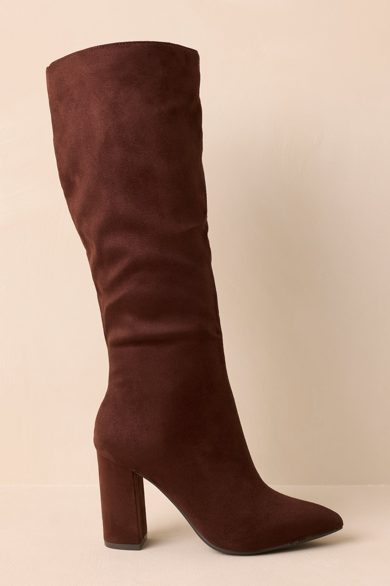 Cropped view of dark brown knee-high boots showing pointed toe and slouched shaft.