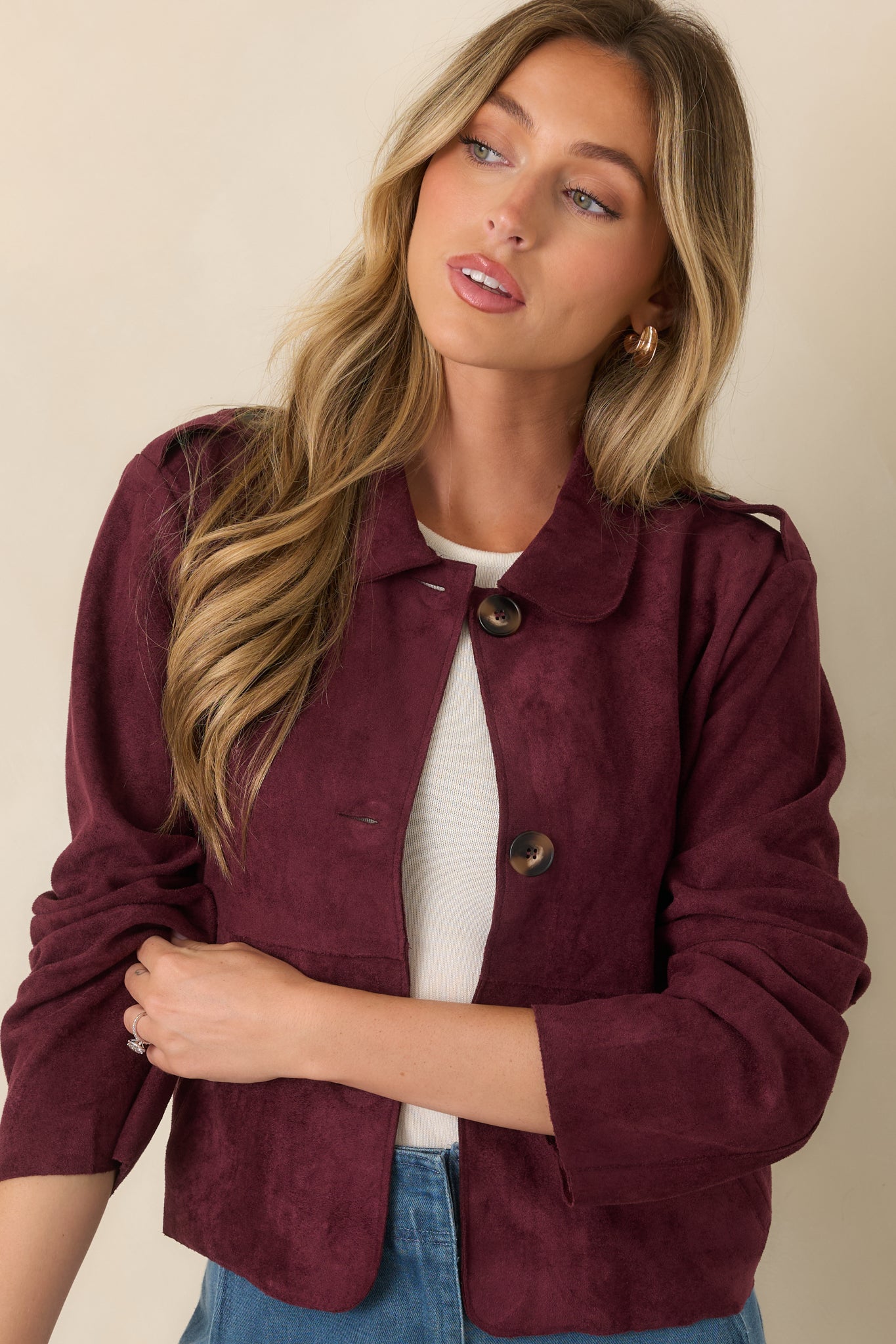 Cropped faux suede jacket highlighting the smooth textured fabric, rounded collar, functional button-front closure, and oversized patch pockets for a structured finish.