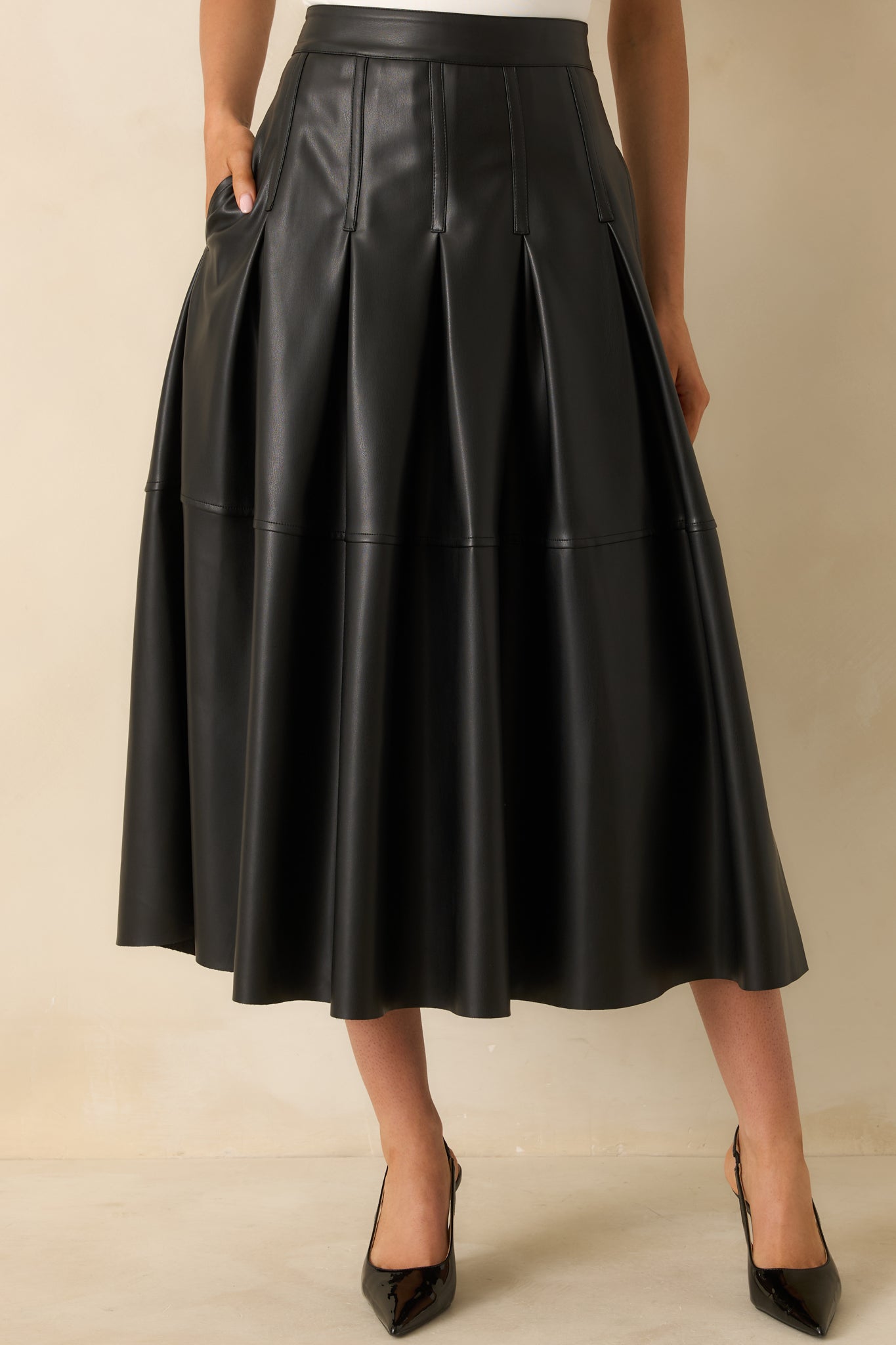 Cropped focus on the fluid A-line shape and smooth faux leather texture.