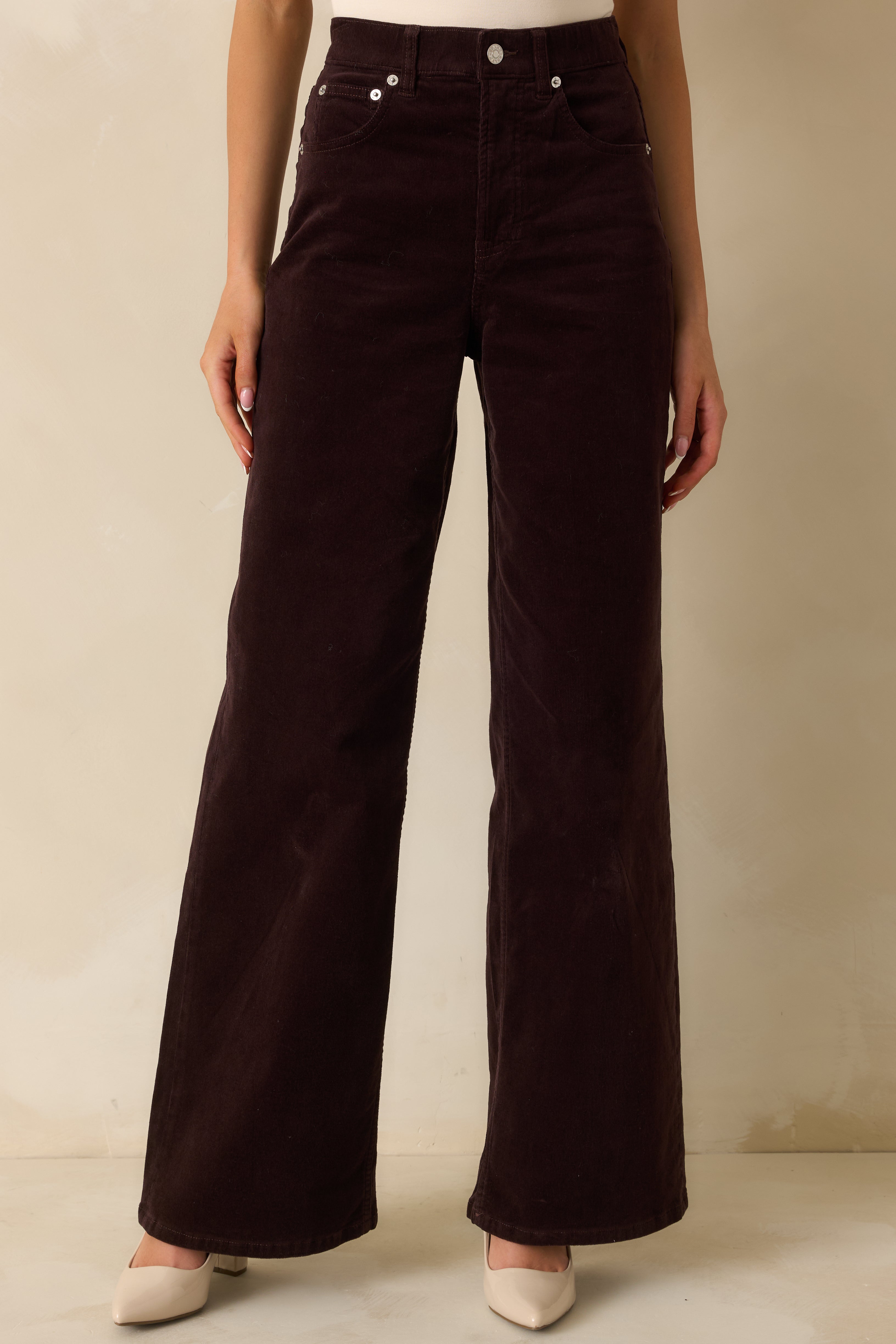 Cropped front detail of high-rise brown corduroy jeans emphasizing texture and pocket design.