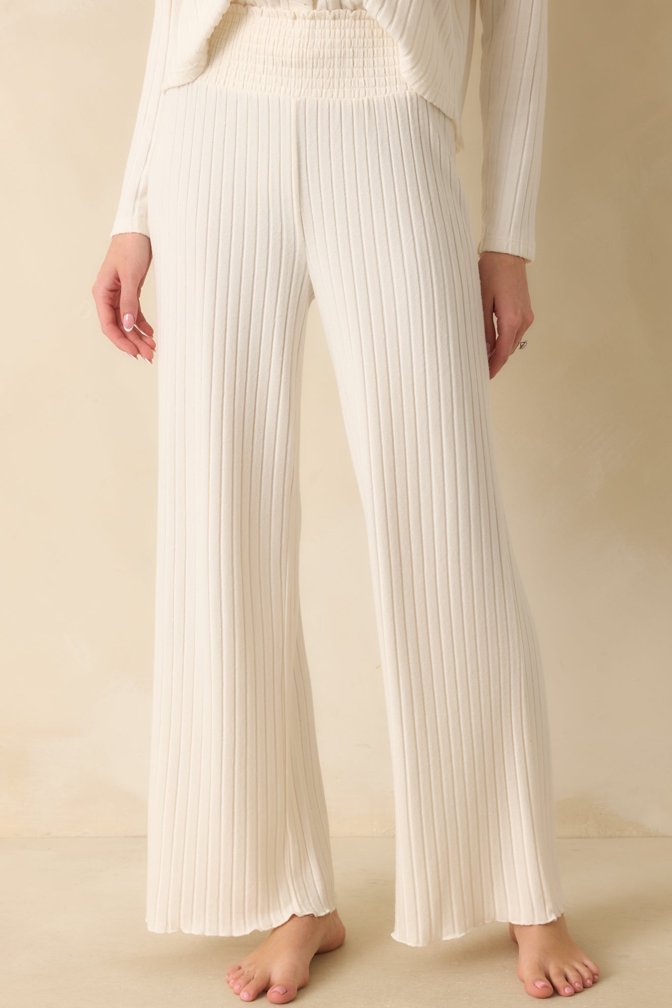 Cropped front view showing the ribbed texture and upper leg of the ivory pants.