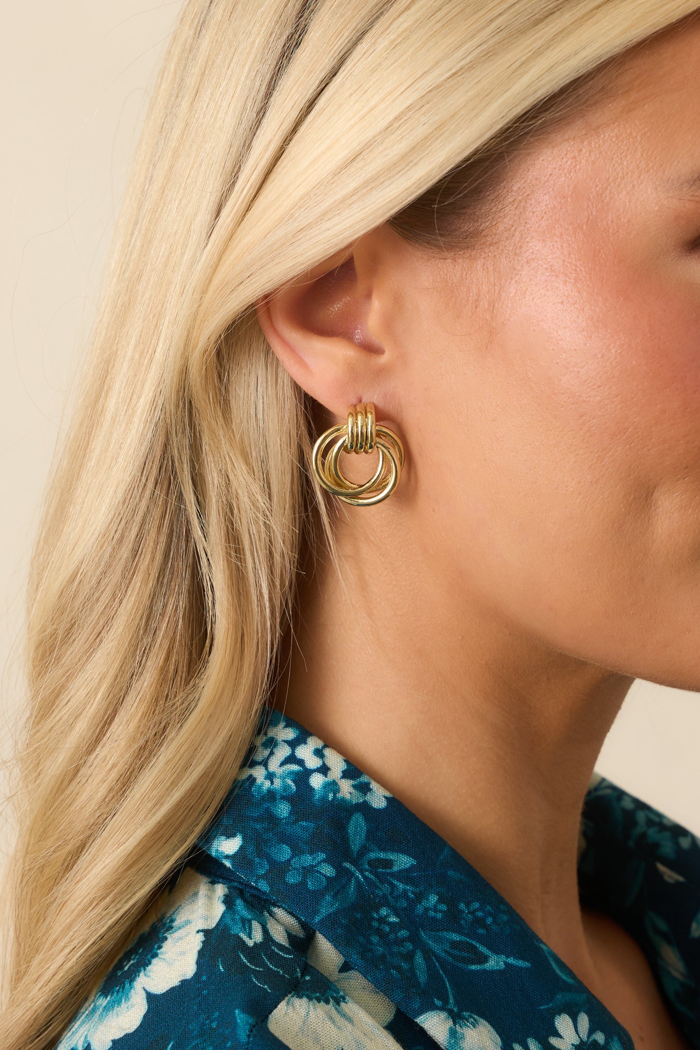 Cropped photo showing the gold earrings’ stacked multi-hoop design with three interlinked polished rings.