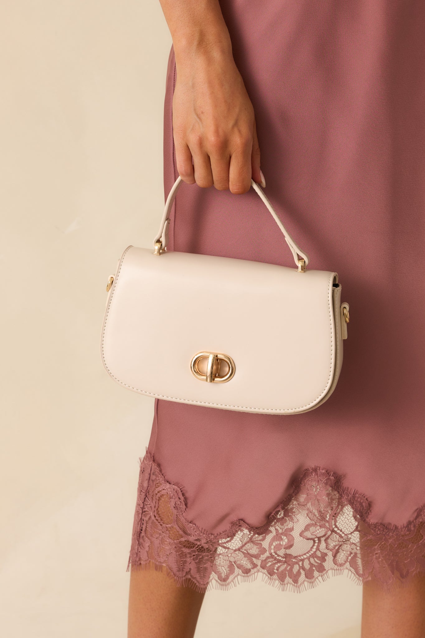A cropped angled shot of the handbag focusing on the flap closure and polished gold hardware.