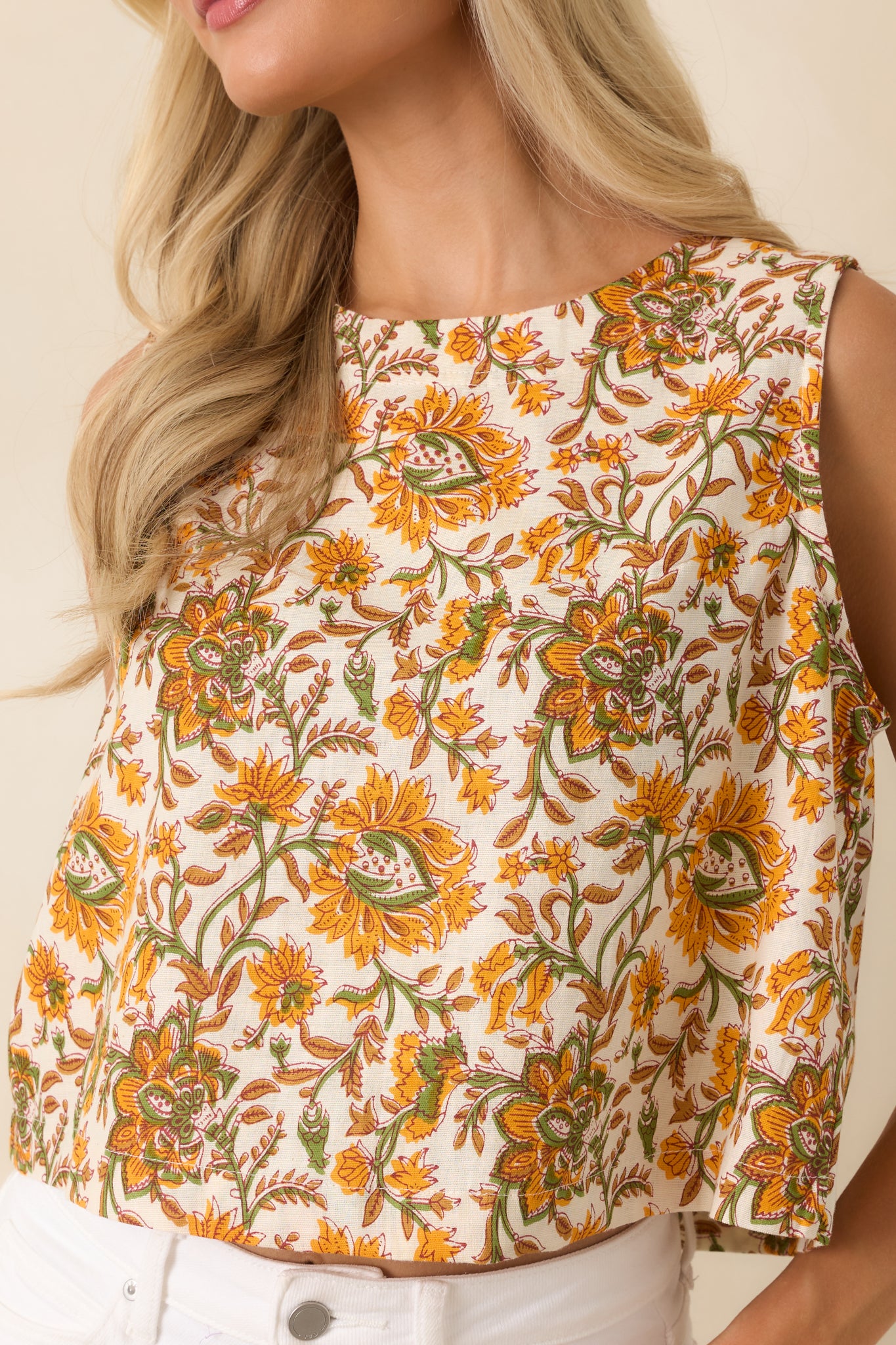Close view emphasizing the cropped length, high neckline, and soft floral print of the sleeveless top.