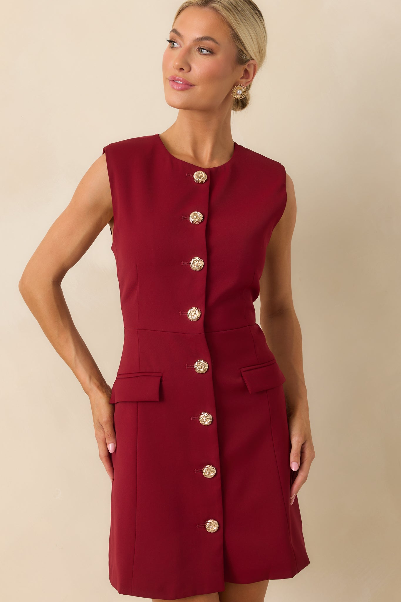 Cropped image highlighting the waist area and the fitted structure of the dress with gold button detailing.