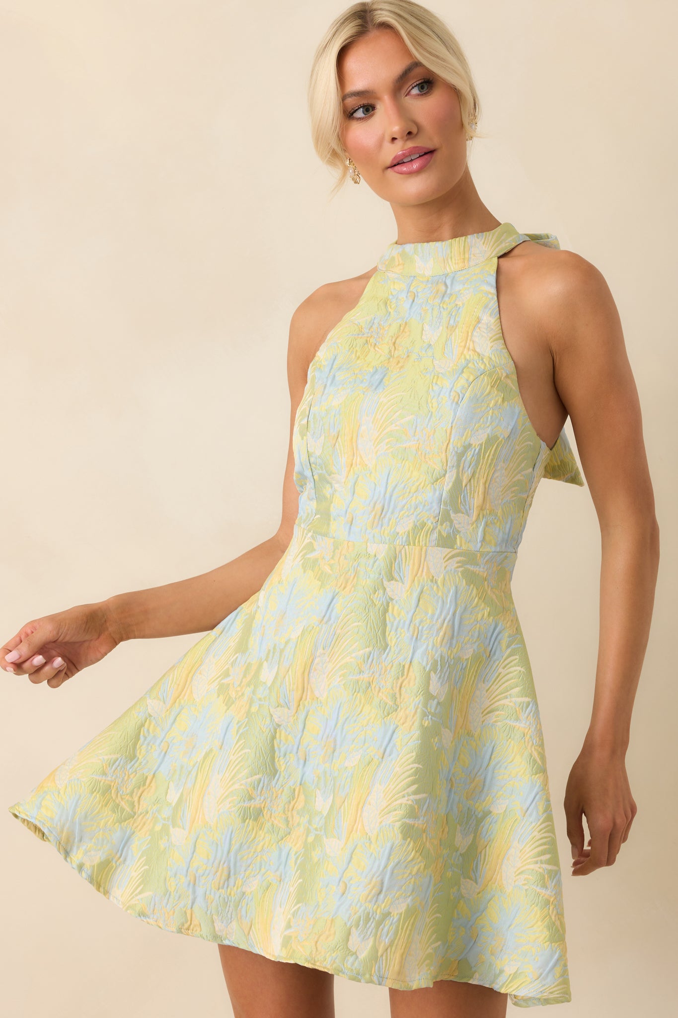 Cropped image showing the waistline and floral texture of the light green mini dress.