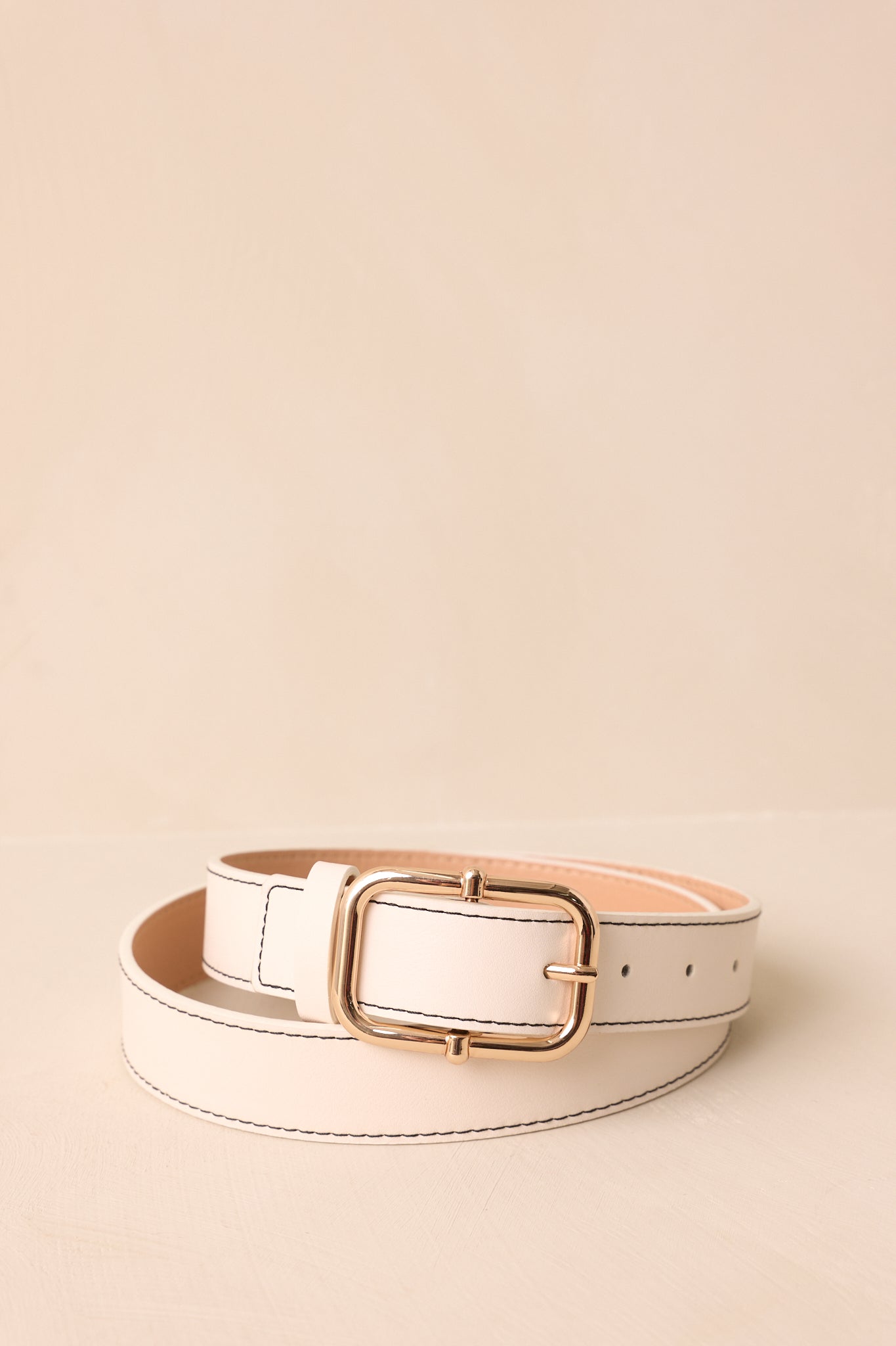 Cropped image highlighting the ivory stitched edges and adjustable fit of the faux leather belt.