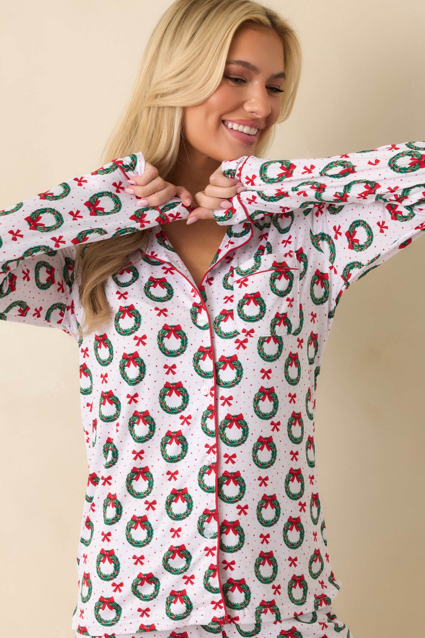Cropped view showing the long sleeve cuff, festive wreath and bow print, and fabric texture.
