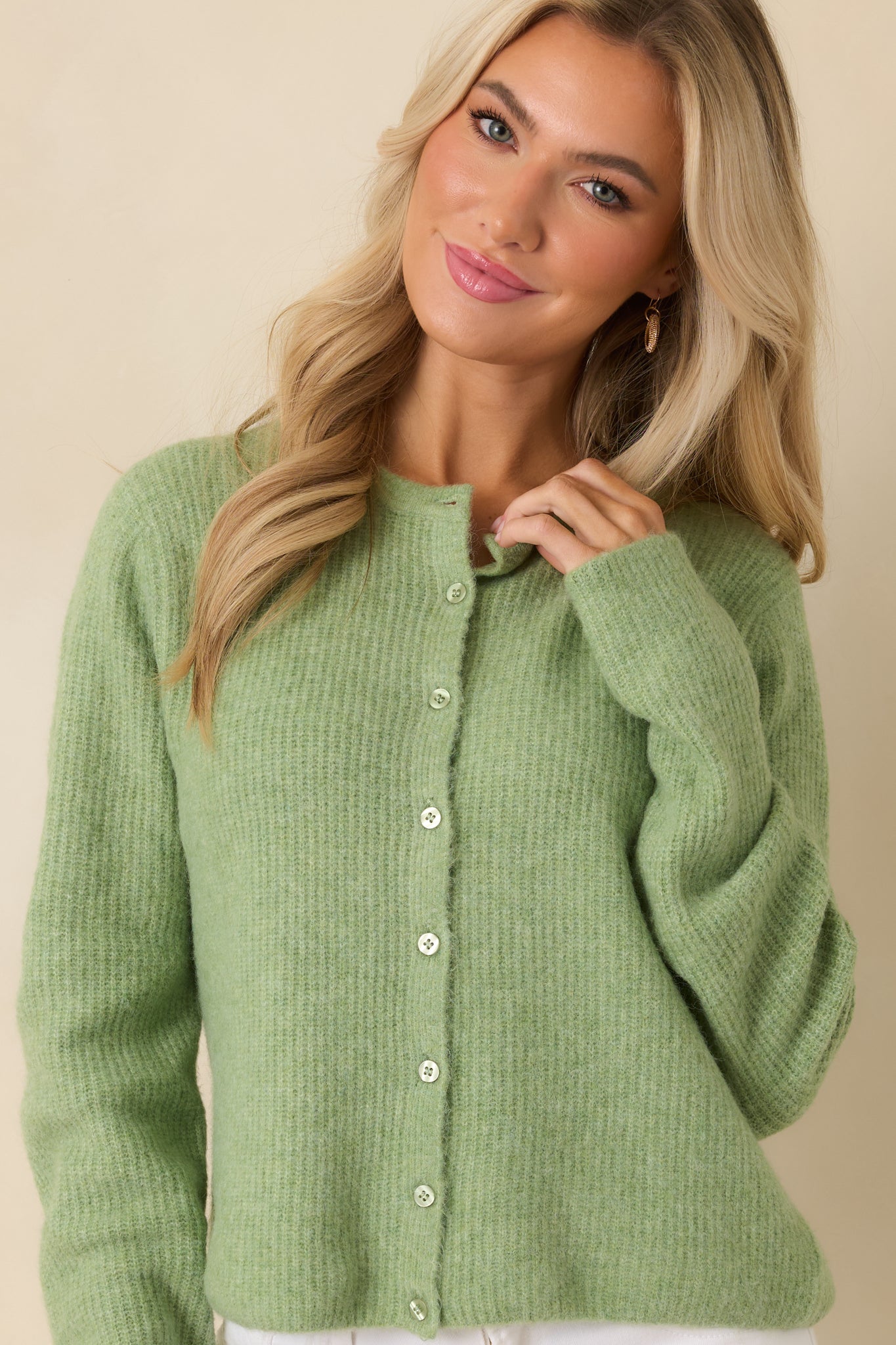 Cropped view emphasizing long sleeves and subtle texture of lightweight green cardigan.