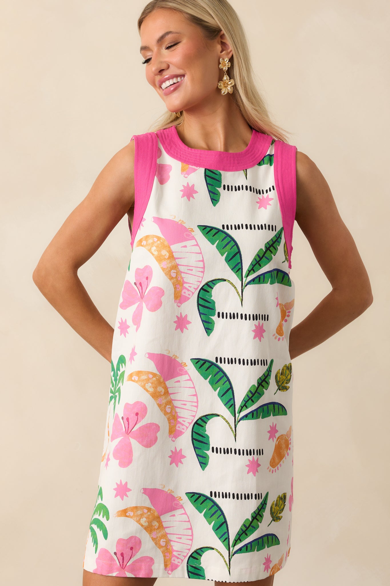 Focused crop of the lower hemline displaying the shift silhouette and bold pink trim against the tropical print.