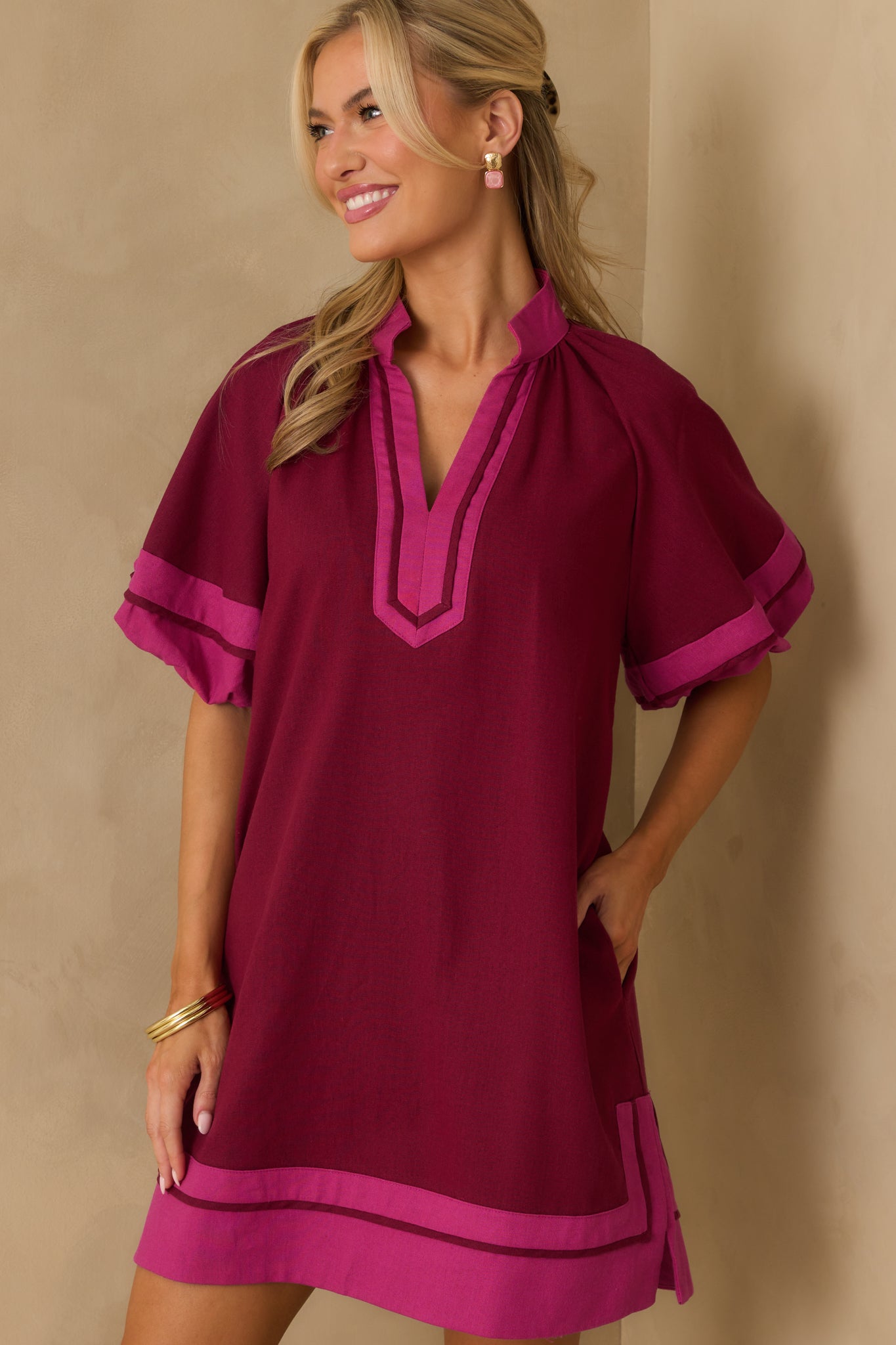 A cropped image highlighting the notch v-neckline and pink trim accents on the berry purple dress.