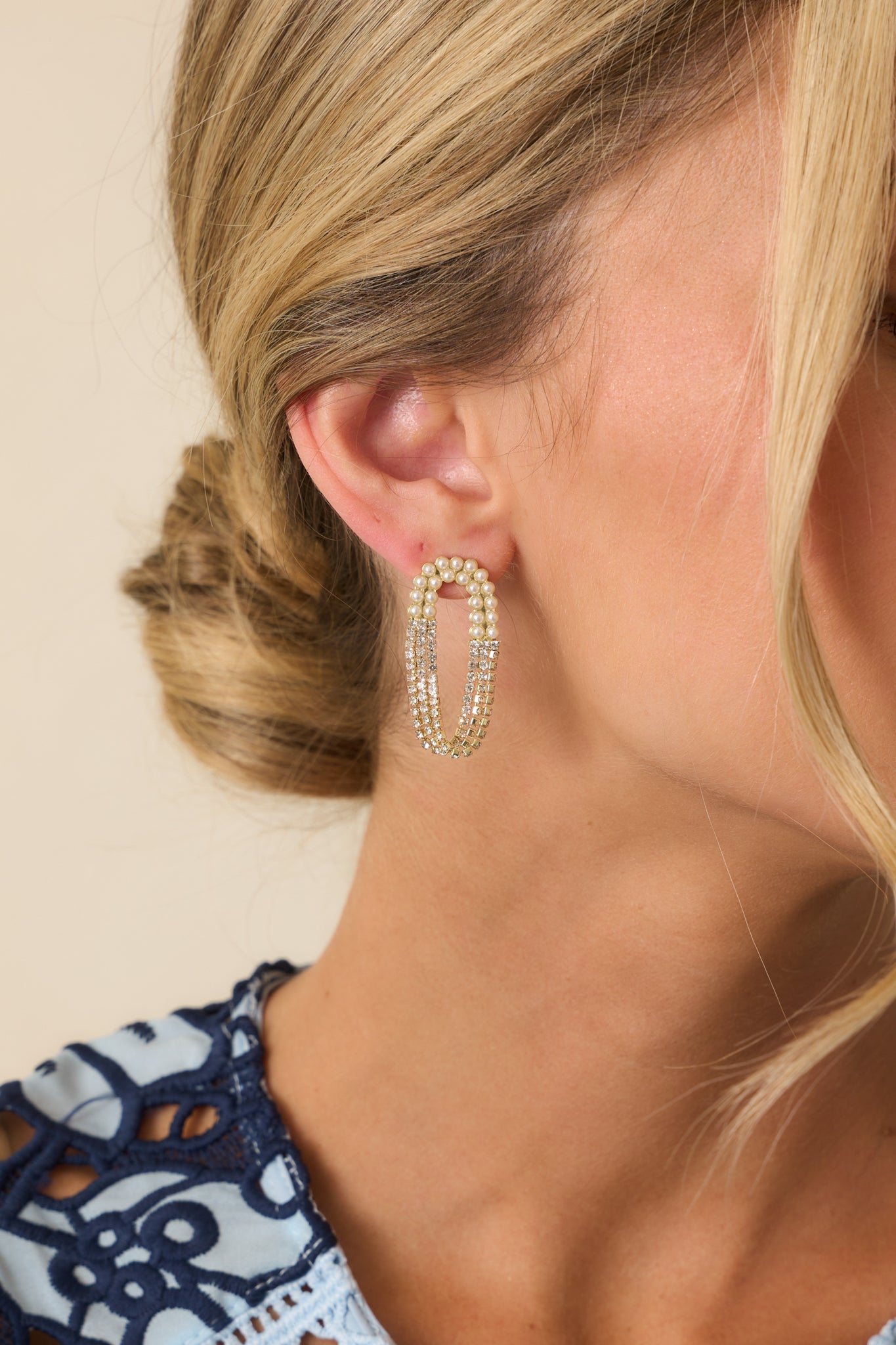 Cropped view of the elongated oval loop earrings featuring multiple chains with faux pearls on one side and rhinestones on the other.