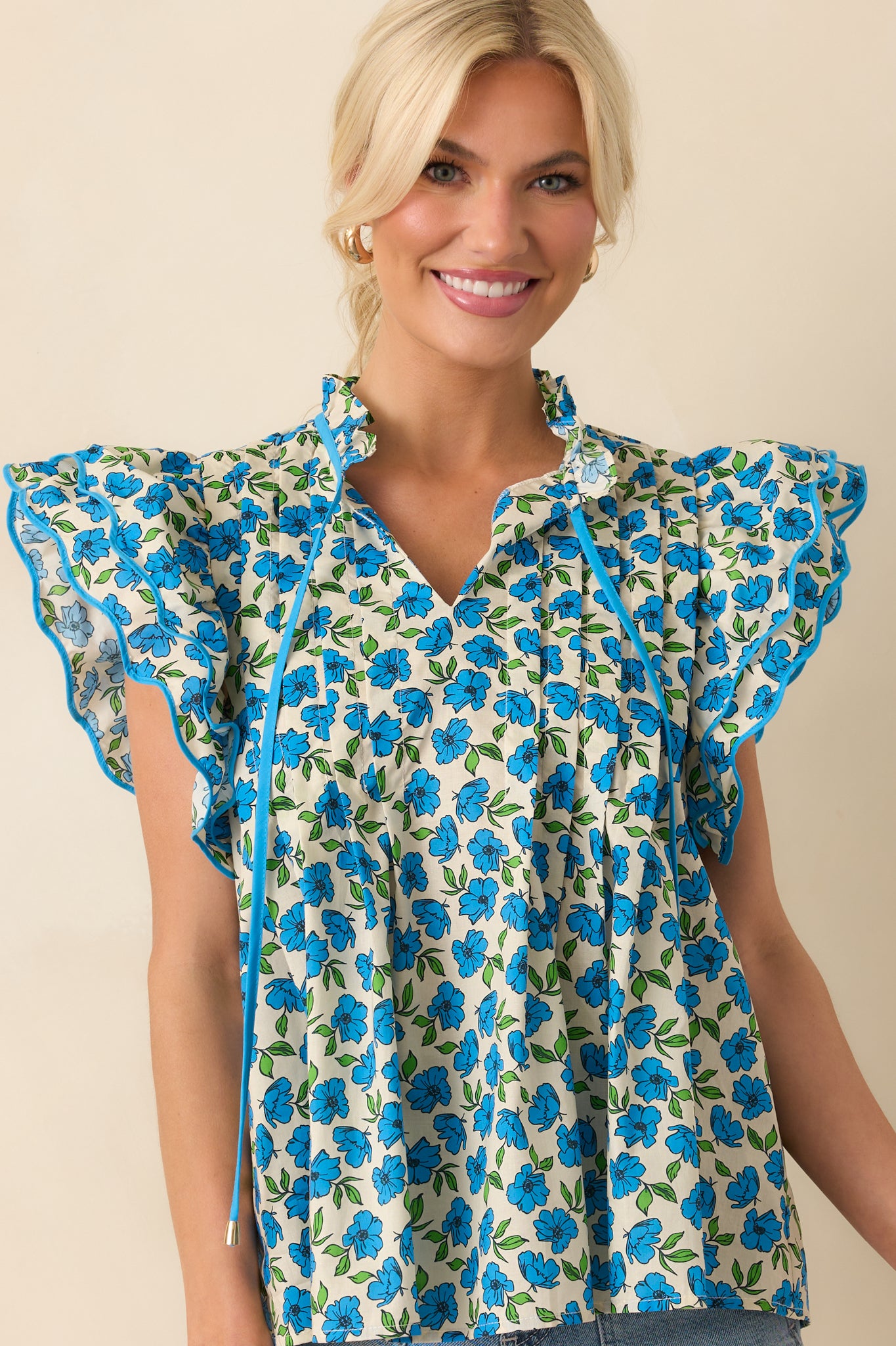 Cropped photo highlighting the flutter sleeves and the edge of the floral print on the blue top.