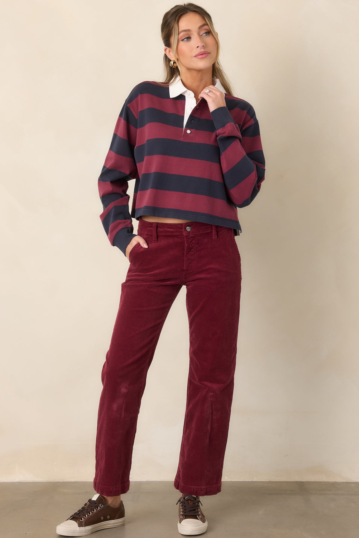 Cropped rugby polo top with wide horizontal stripes, a contrasting white point collar, partial button placket, long sleeves, and relaxed shoulders.