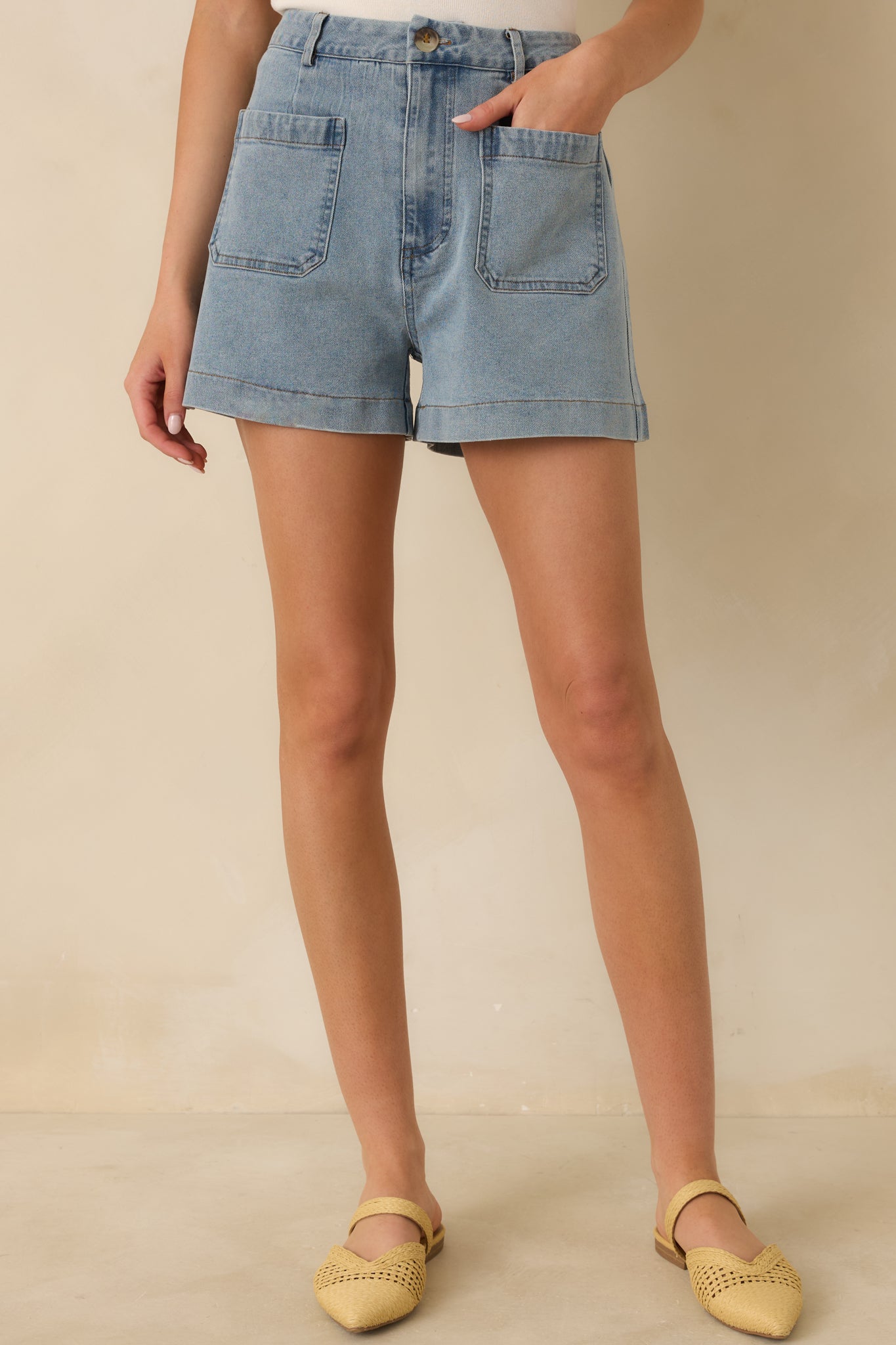Cropped view of the shorts showing the button and zip fly closure, belt loops, and straight leg opening.