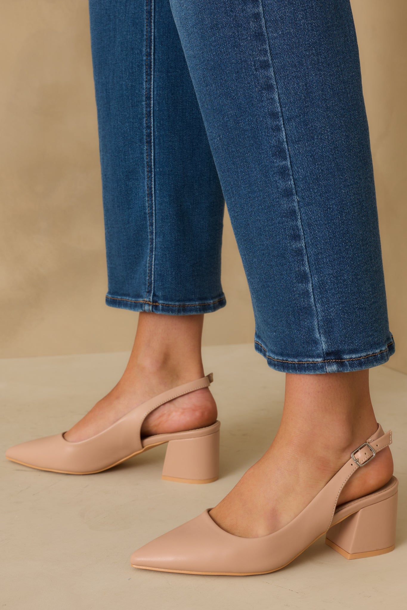 A cropped shot showcasing the pointed toe design, adjustable back strap, and thick heel.