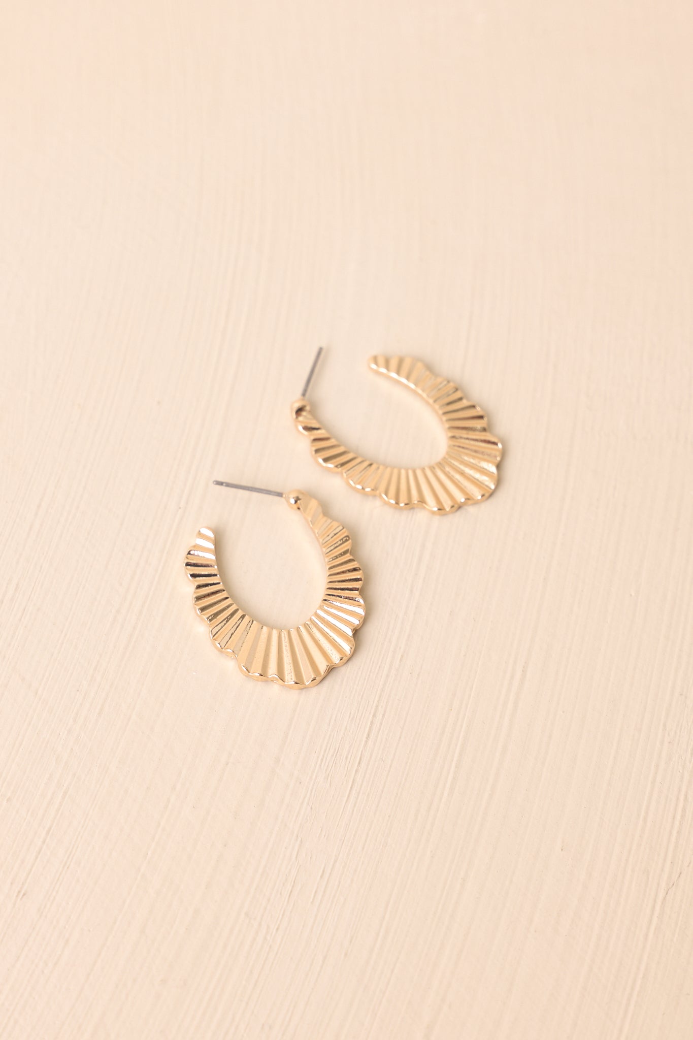A close-up cropped shot highlighting the textured lines along the scalloped hoops and the secure post backings.