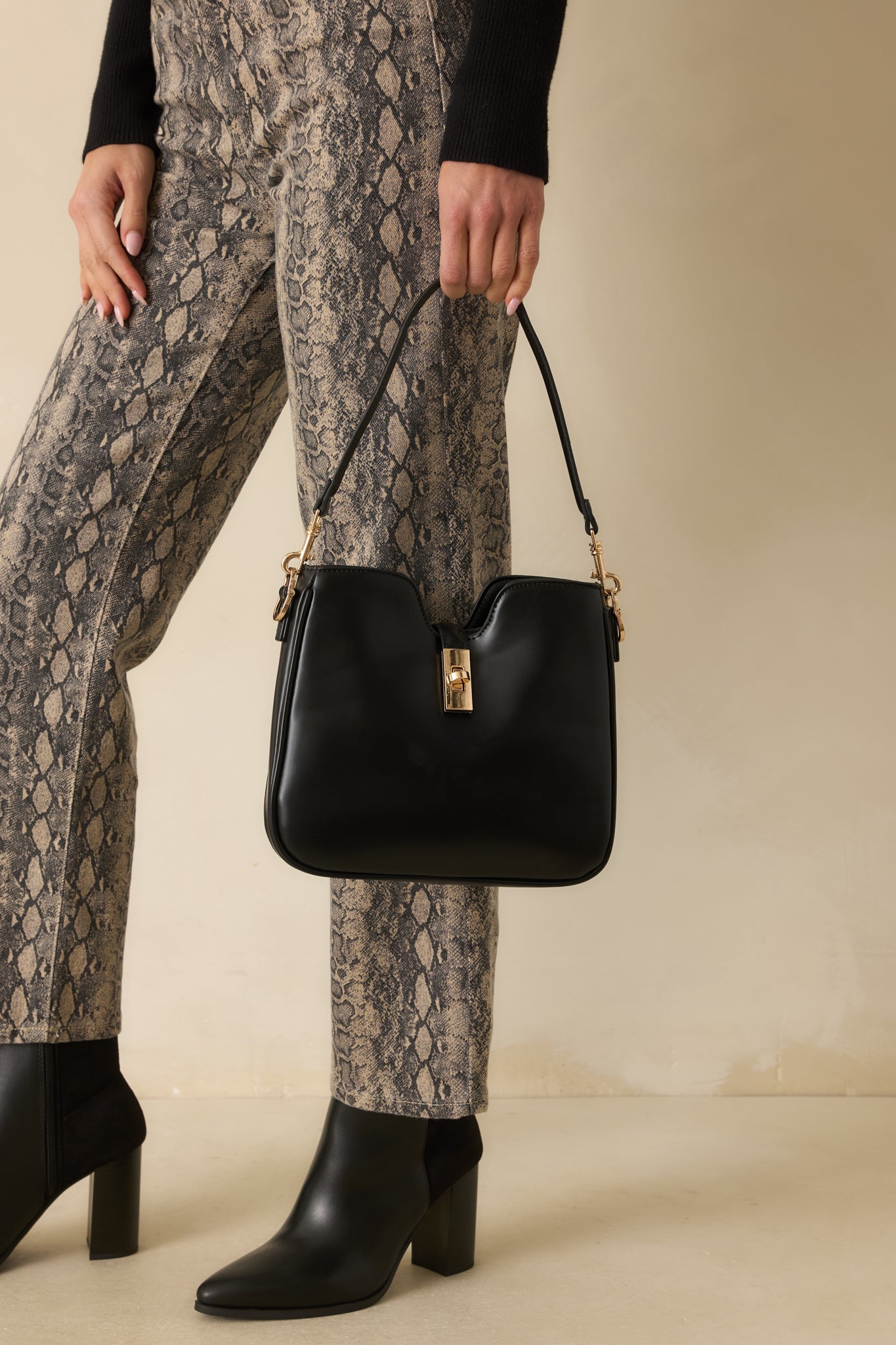 Cropped photo focusing on the top section of the bag, showing the gold turn lock closure and smooth faux leather texture.