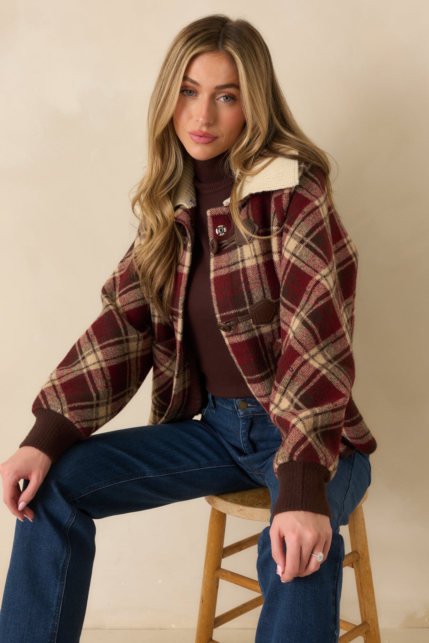 Cropped upper torso view highlighting fold-over knit collar, button closures, and plaid pattern.