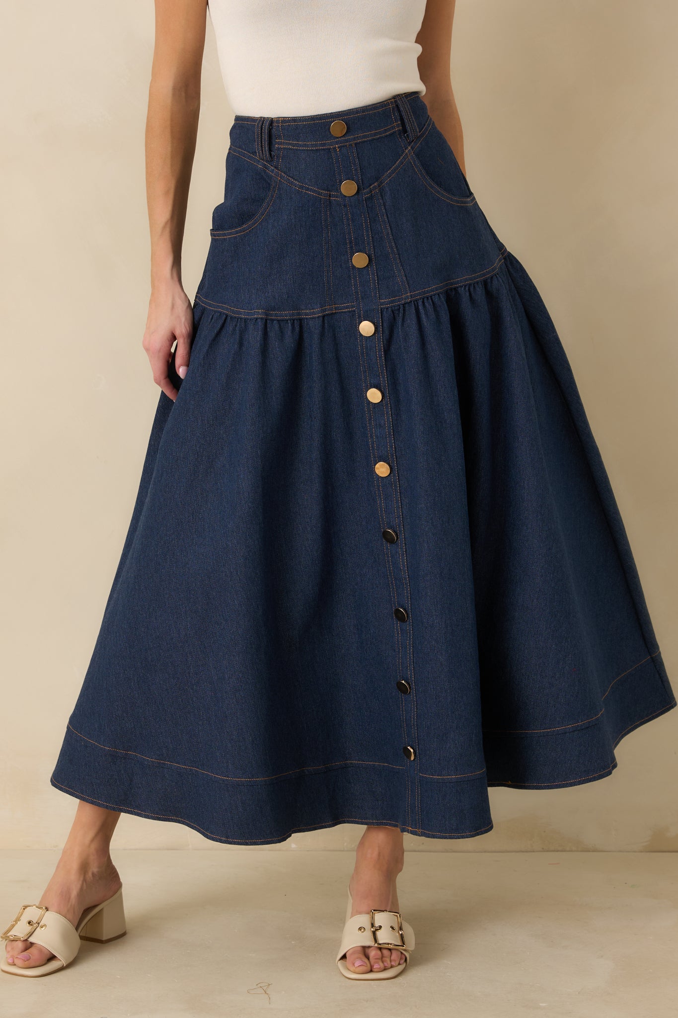 Cropped front view of the denim maxi skirt focusing on the gold-tone buttons and high-rise waistband.