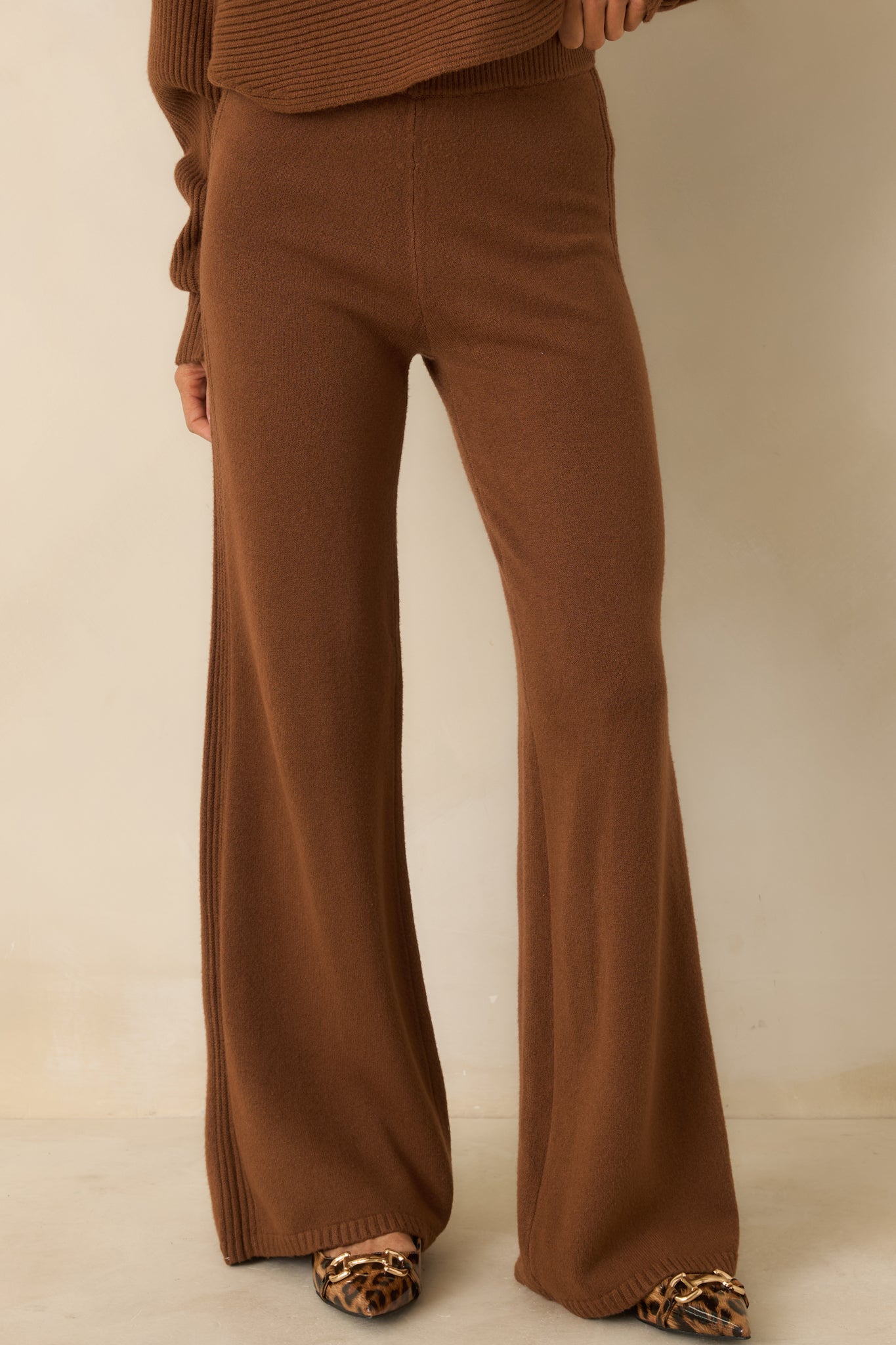 Cropped view highlighting high-rise waistband and wide-leg design of brown knit pants.