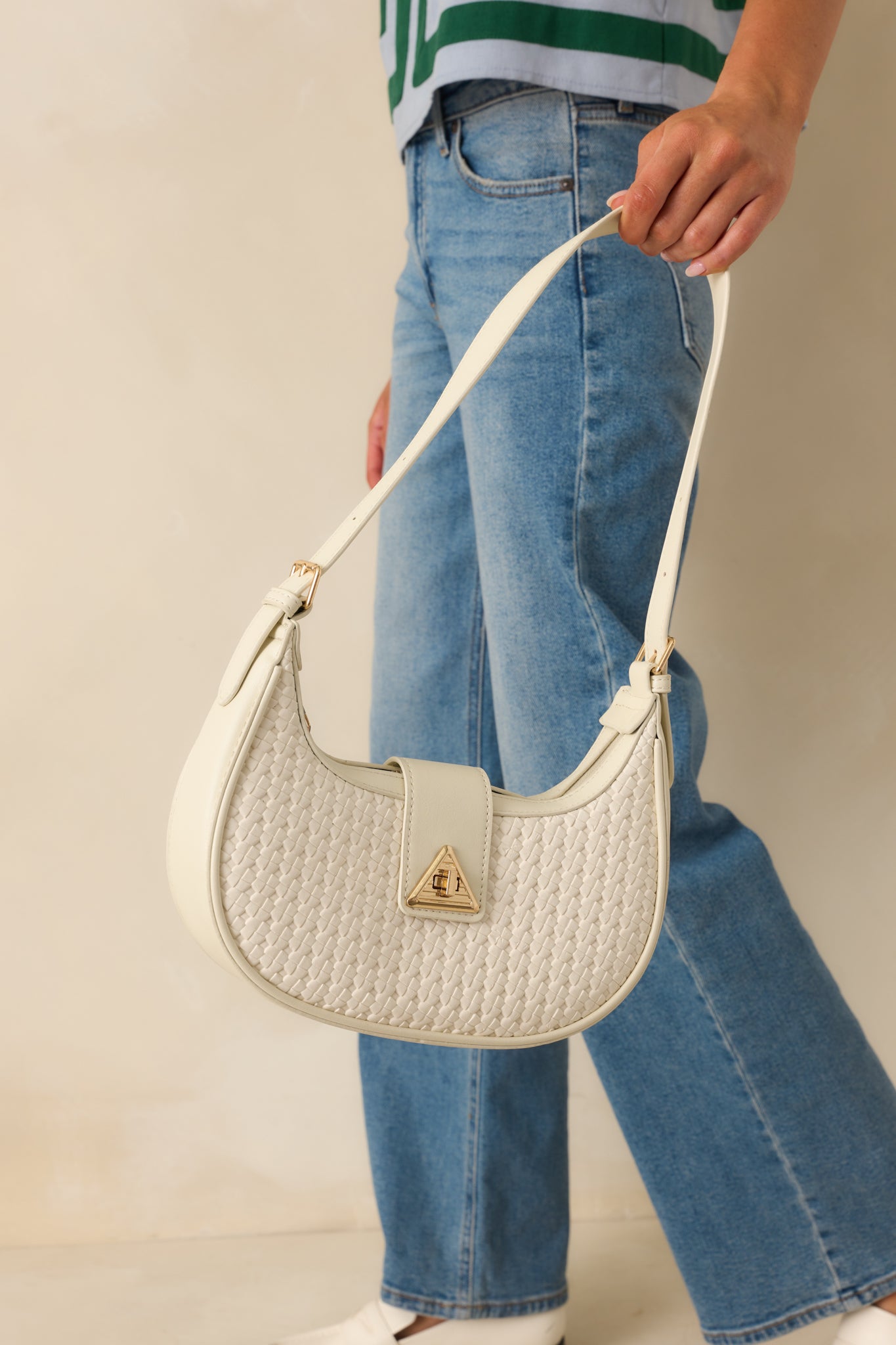 A cropped side view highlighting the curved silhouette, gold zipper closure, and flat strap.