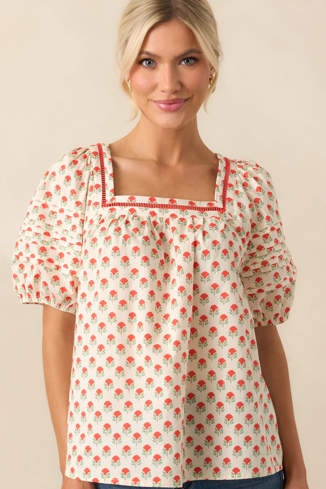 A cropped view highlighting the detailed ladder lace trim around the square neckline of the red floral printed top.