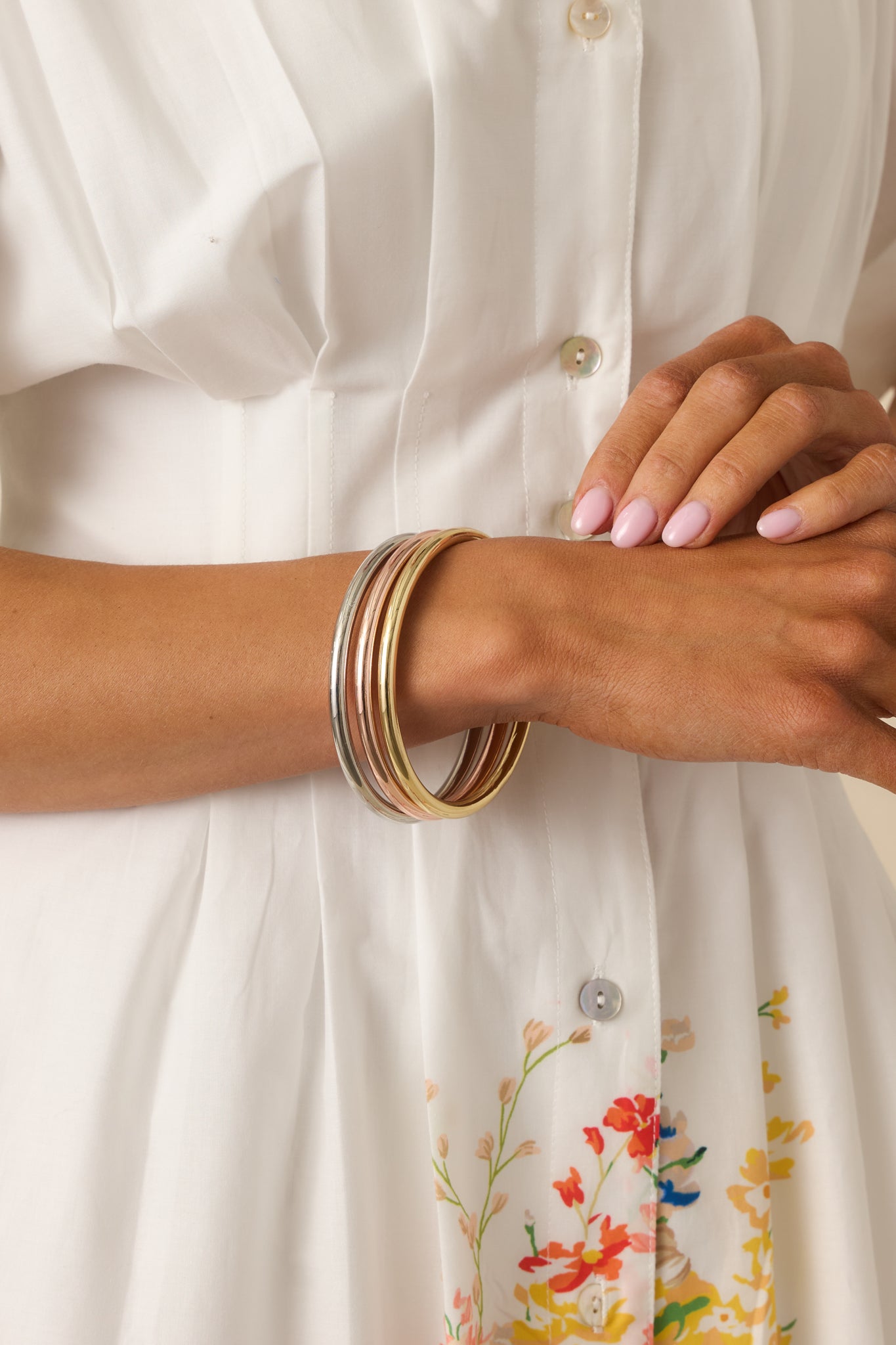 Cropped view of three metal-tone rigid bangles showing polished finish and smooth circular shape.