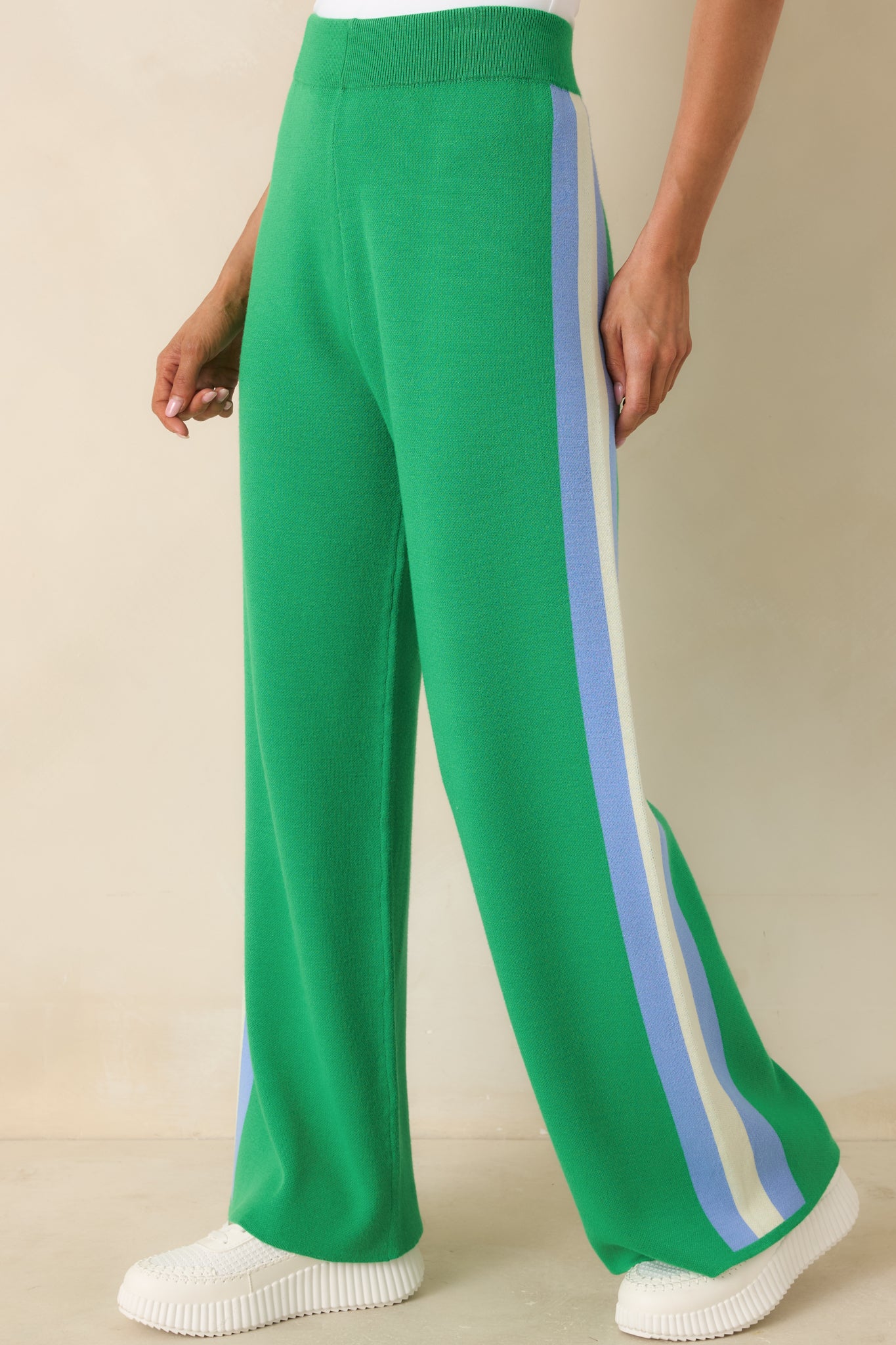Front-facing cropped view of green pants with smooth pull-on fit and side stripe.