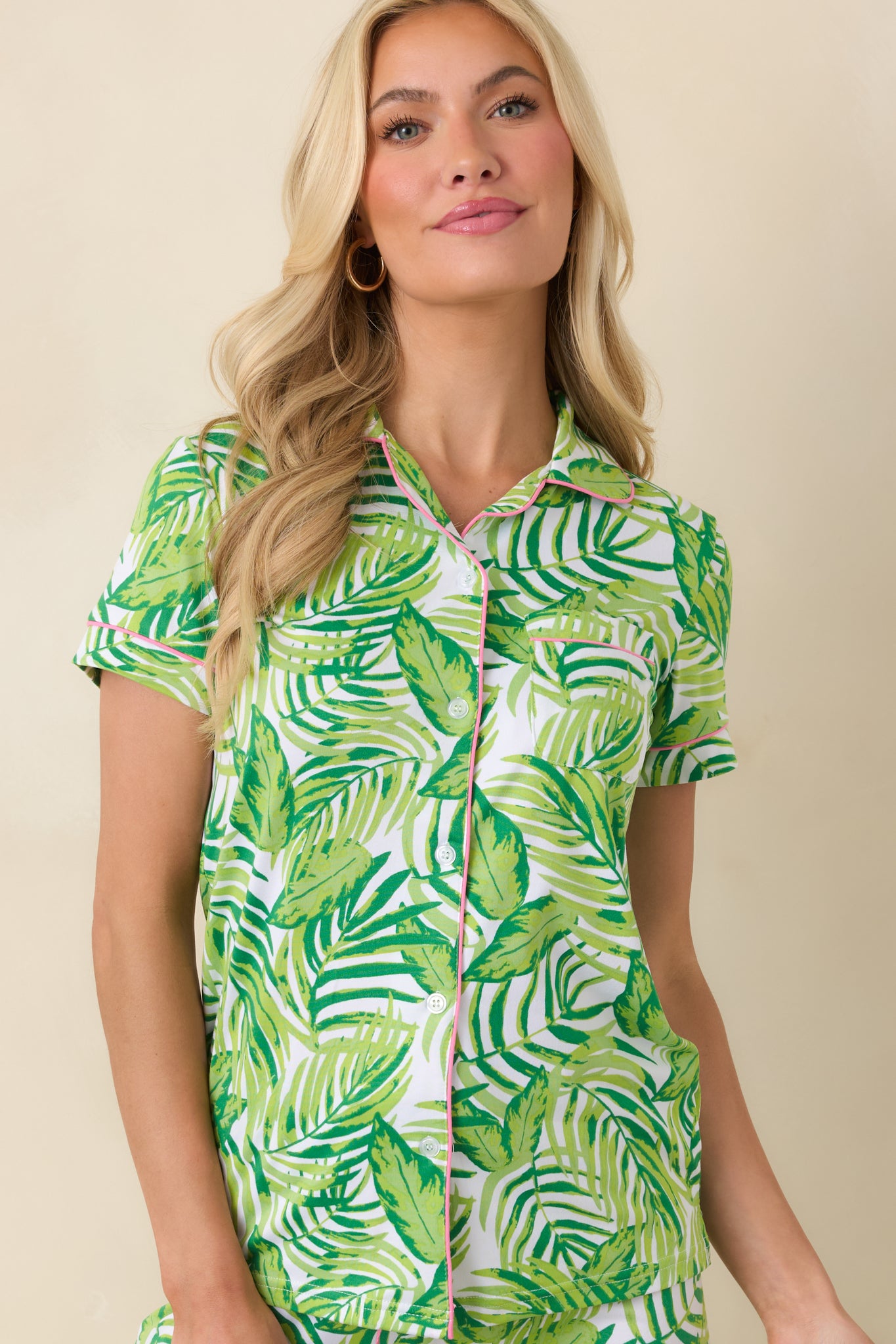 Cropped view of tropical print top highlighting notched collar, front chest pocket, and pink piping