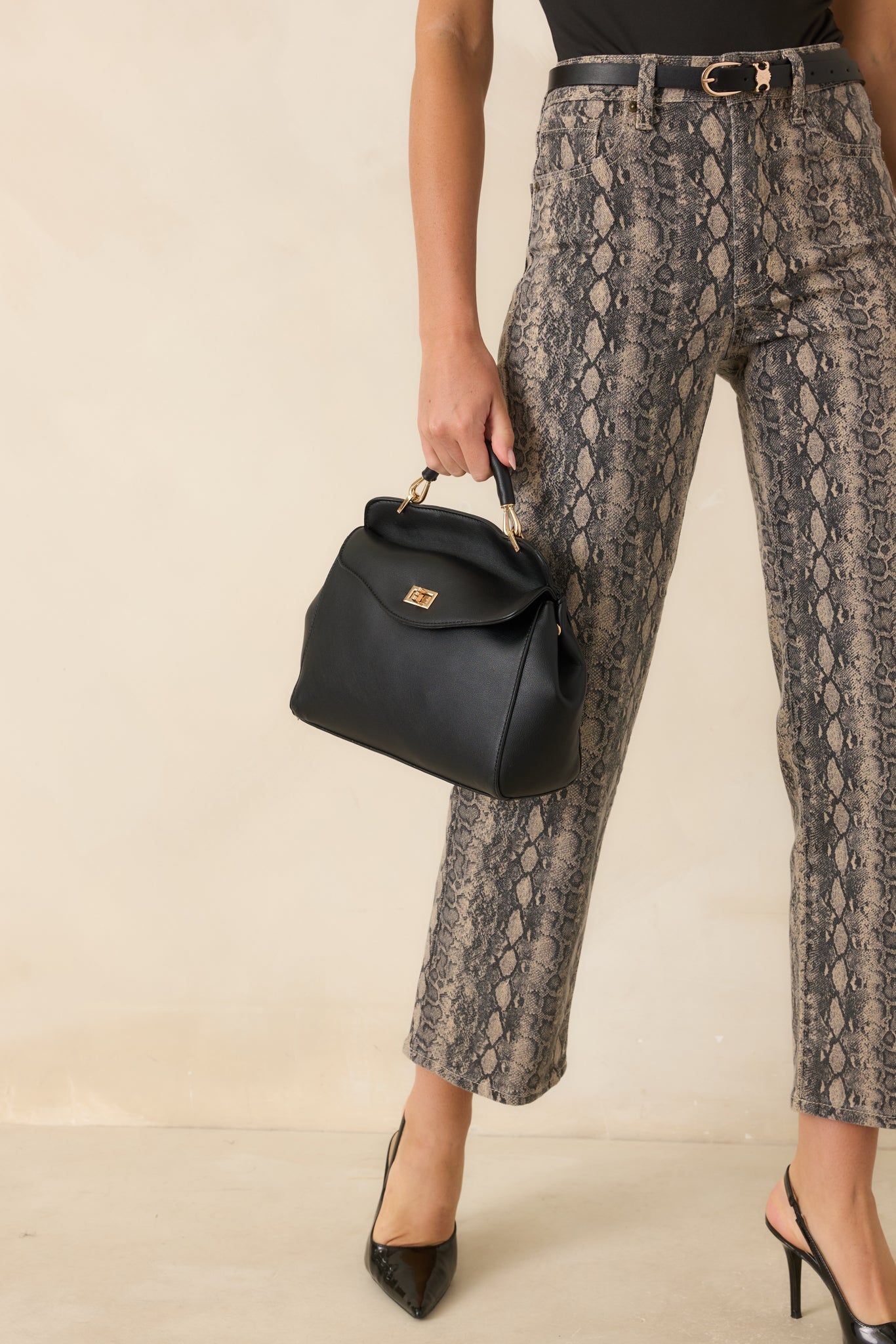 Close view of the handbag showcasing the curved design, smooth faux leather texture, and refined gold-tone twist closure.