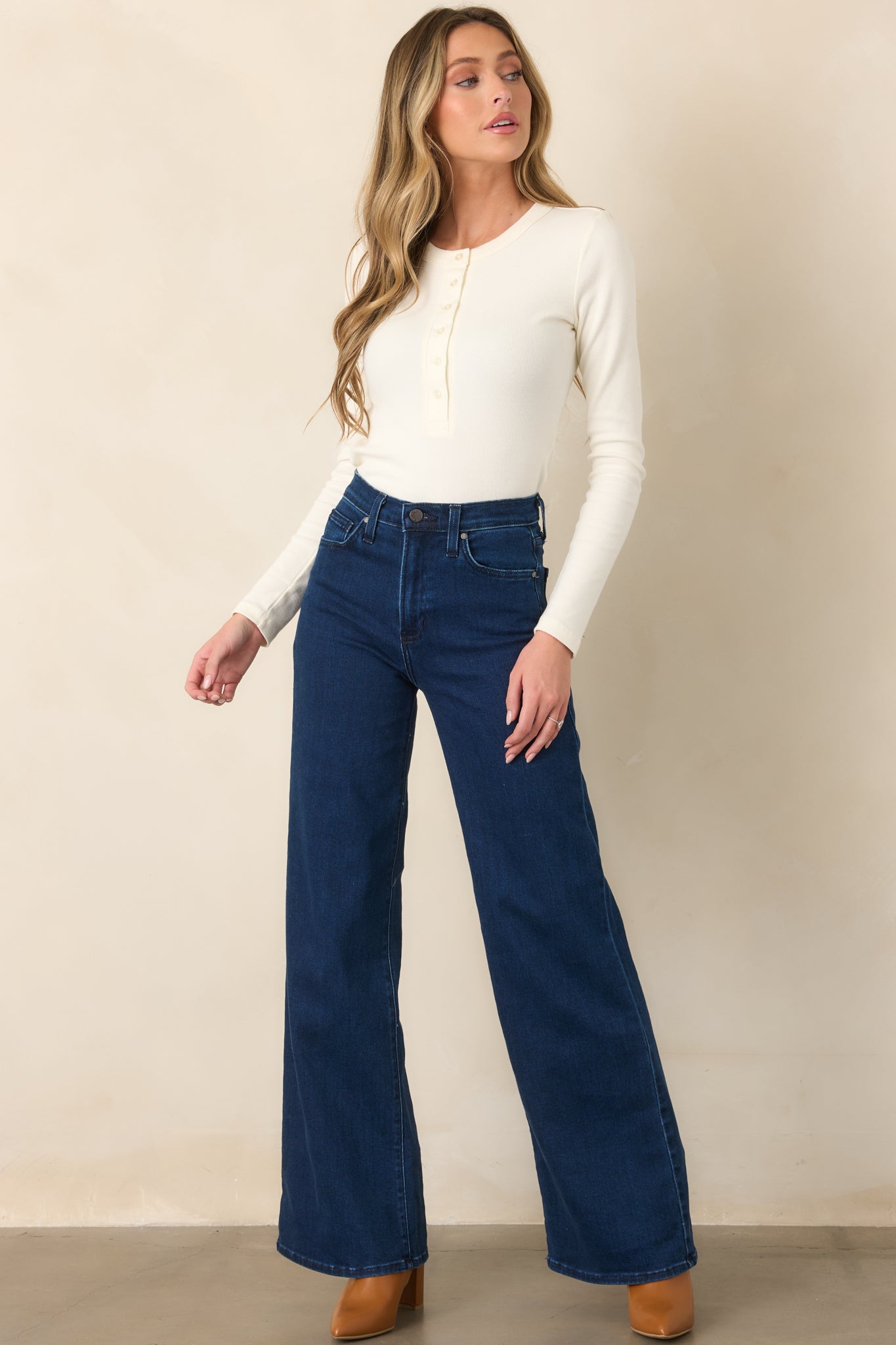Deep blue denim jeans featuring a high-rise fit, traditional zip-button closure, and relaxed wide legs with practical pocket styling.