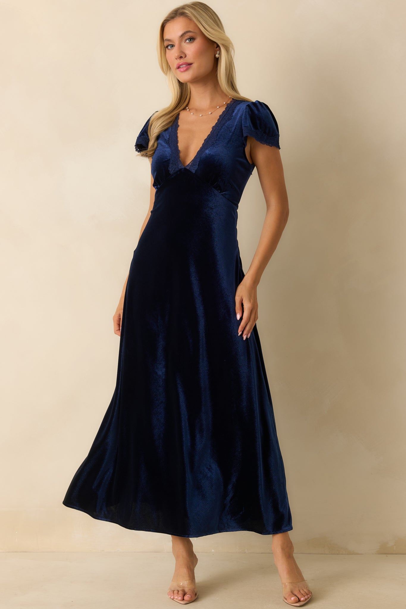 Dark blue velvet maxi dress with V-neckline trimmed in lace, short flutter sleeves, and flowing A-line skirt.