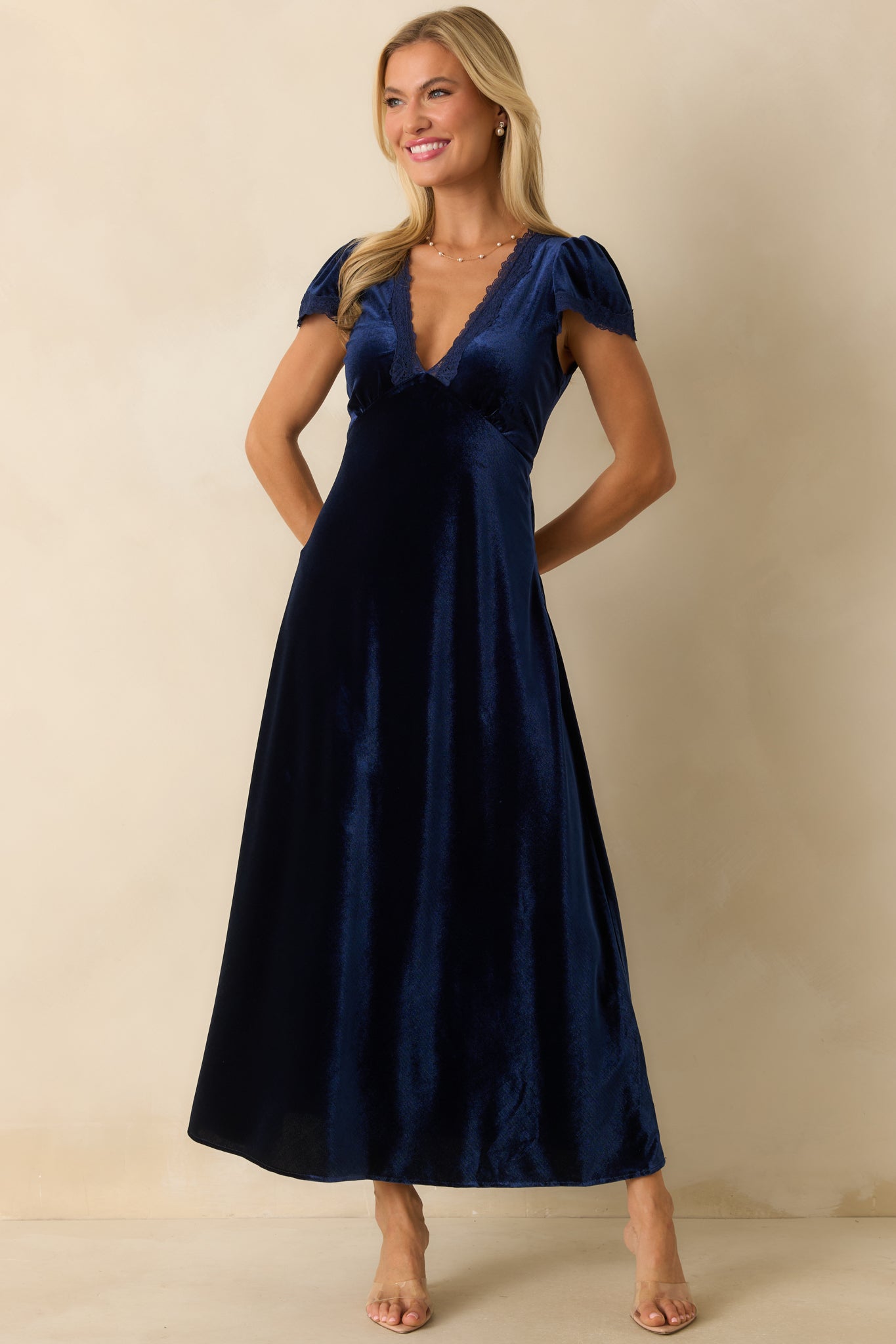 Velvet maxi dress in deep blue highlighting V-neckline with lace trim and short flutter sleeves.