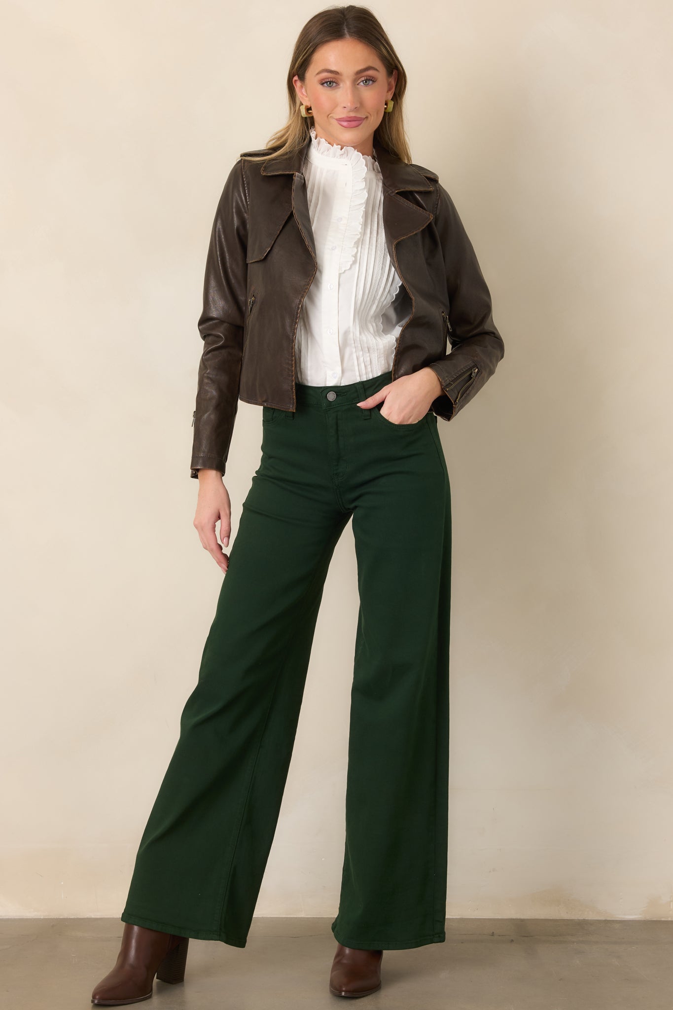 Cropped dark brown jacket defined by an open front, broad notched lapels, zippered side pockets, and sleek faux leather finish.