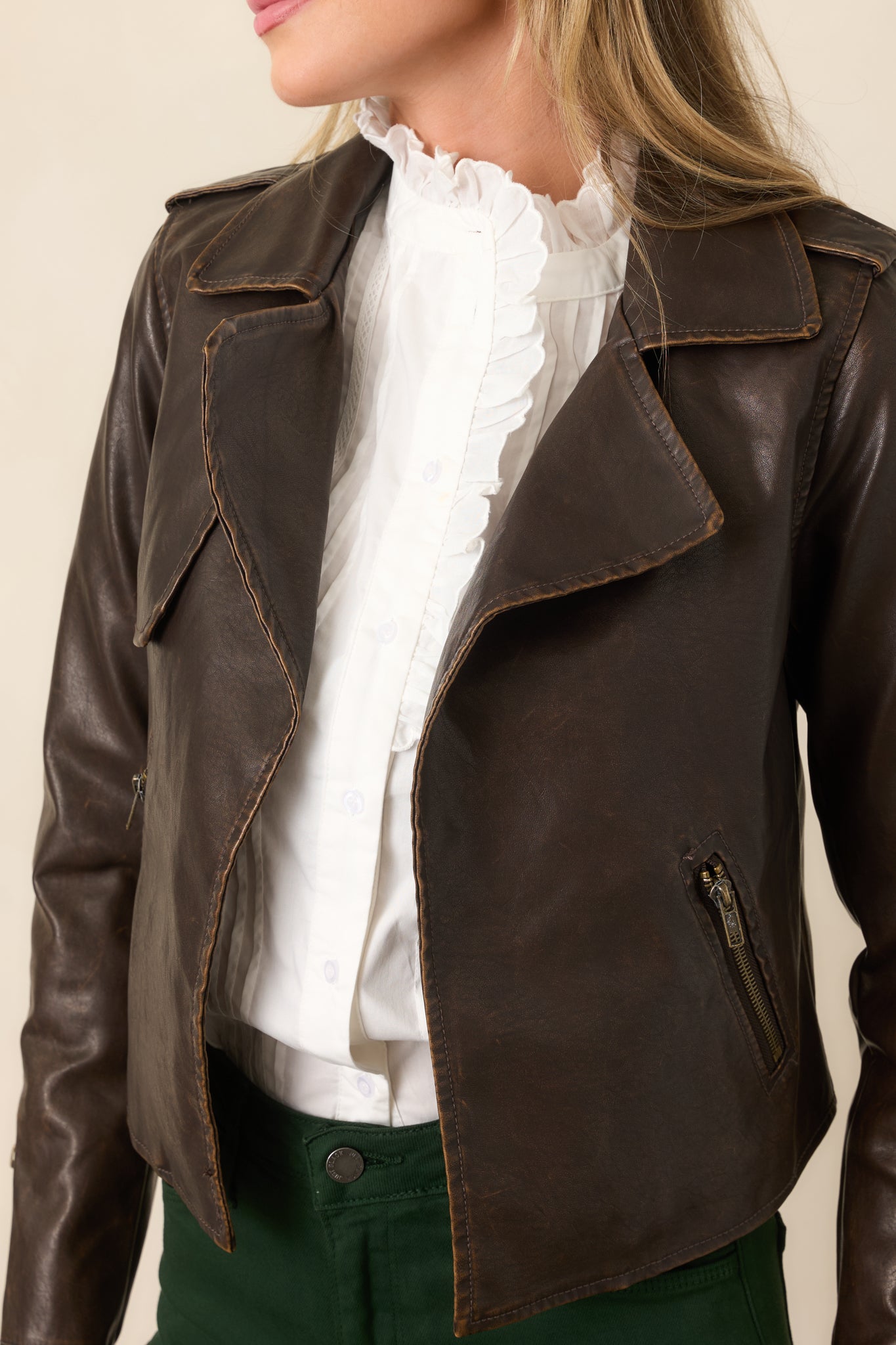 Detailed view highlighting the smooth dark brown faux leather, wide notched lapel, and polished zipper detailing.