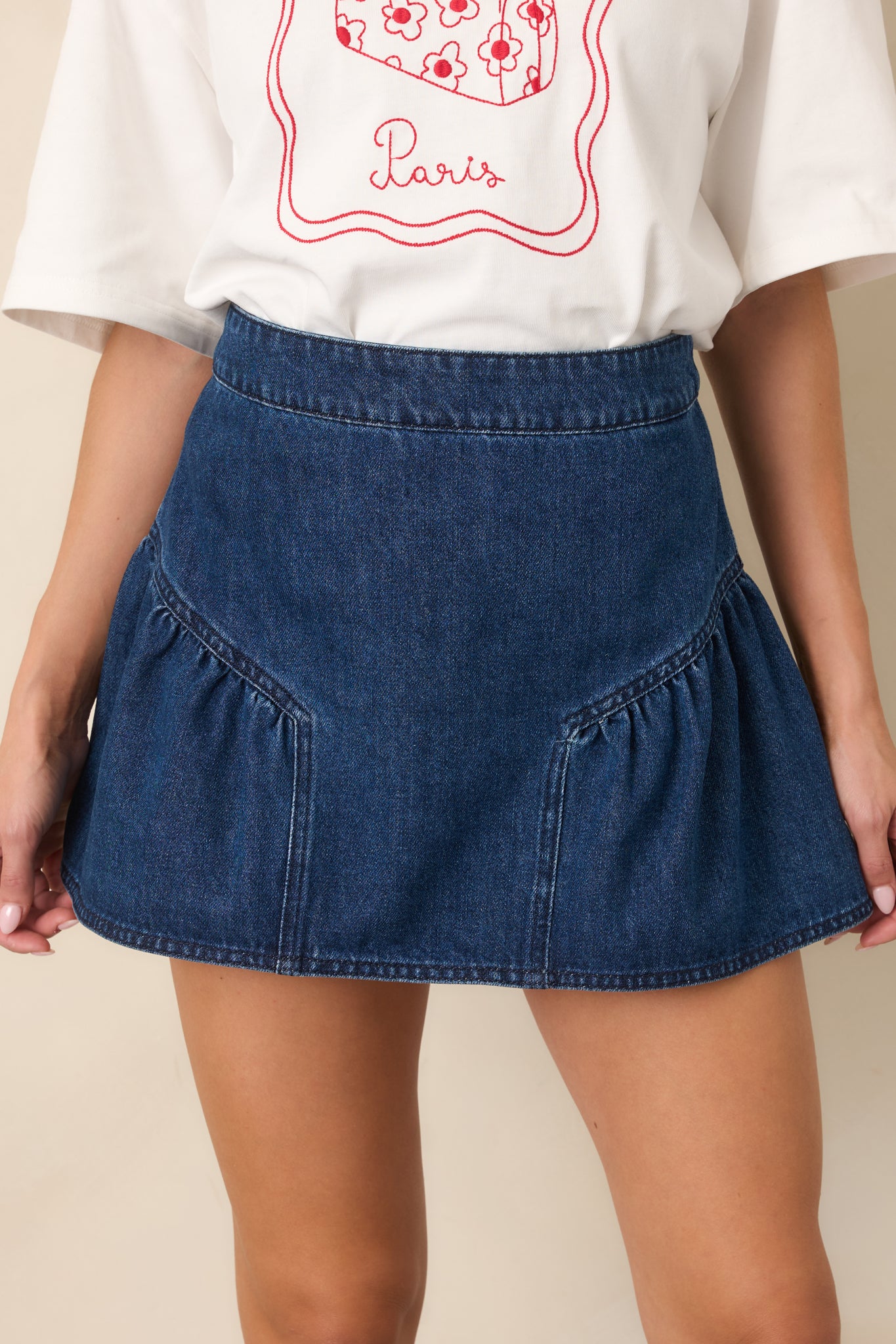 Close-up of the dark-wash denim skirt highlighting the curved panel seams, structured cotton-blend texture, and clean construction.