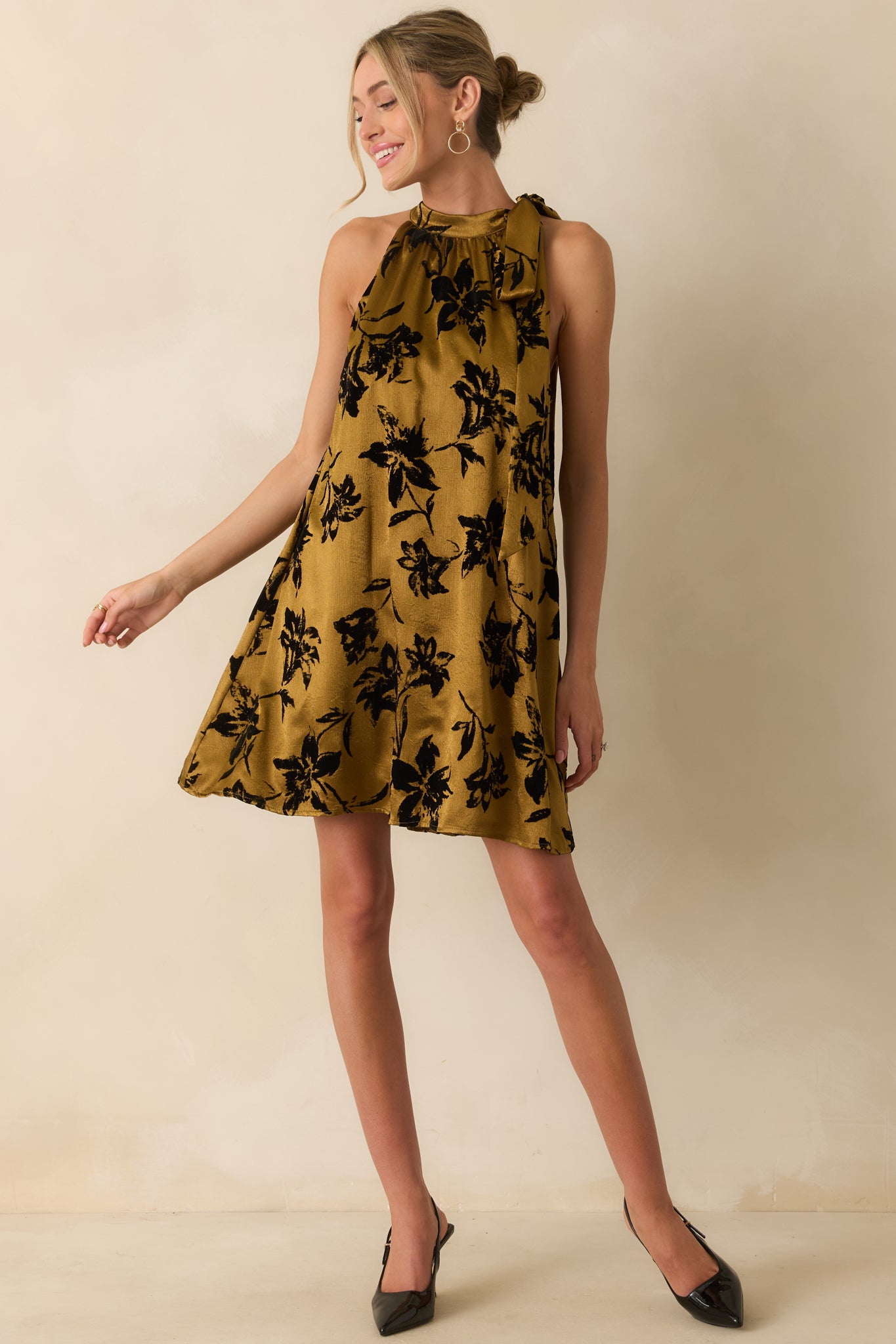 Dark gold satin mini dress featuring a halter neckline with side bow and relaxed A-line silhouette.