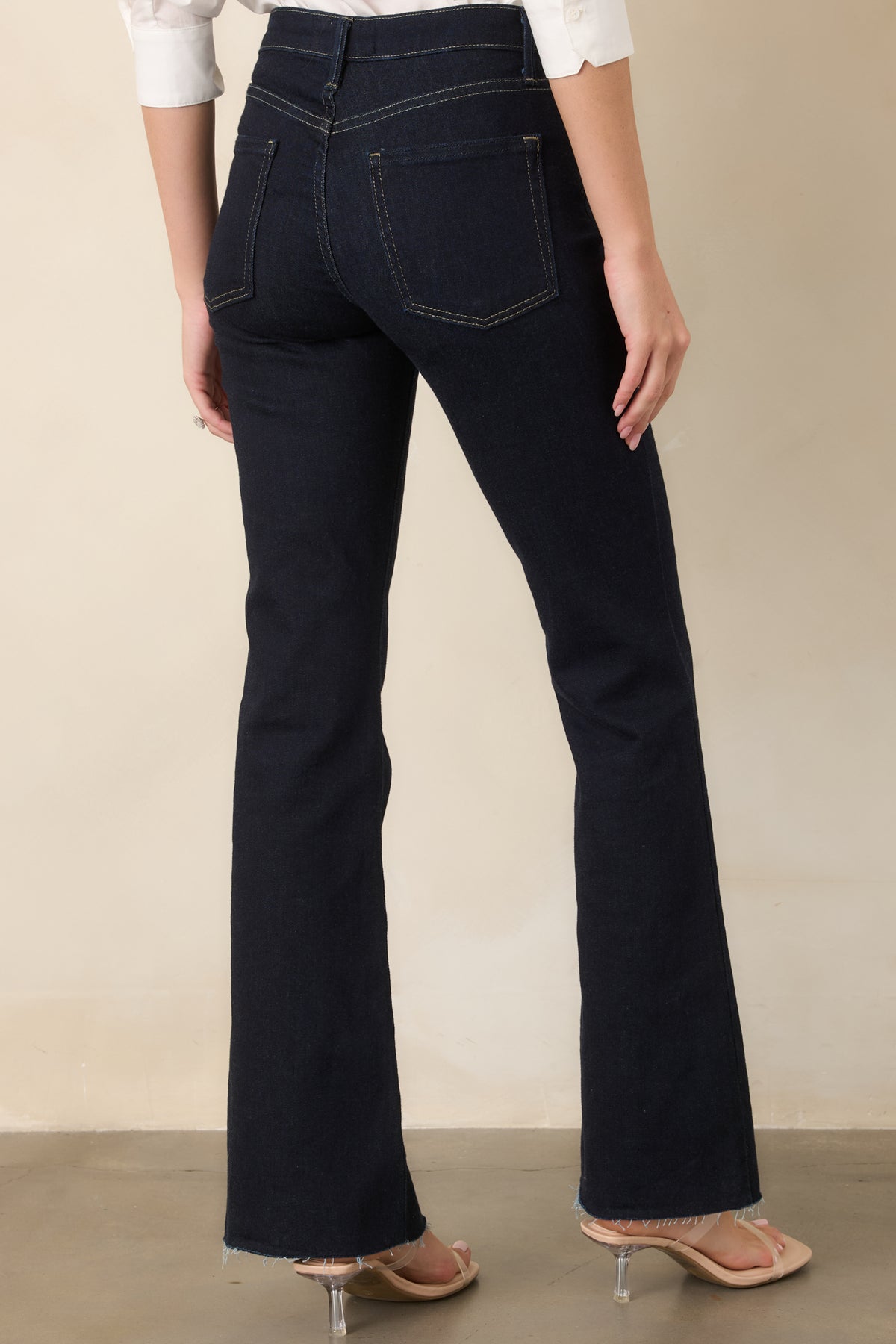 Rear view of the dark indigo flare jeans showcasing the high-rise waistband, classic back pockets, fitted seat and thighs, and dramatic flared legs.