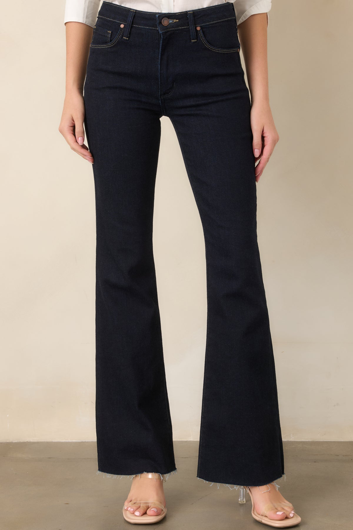 Dark indigo jeans shown in detail with a functional front pocket, belt loop, button-and-zip closure, and clean contrast-free stitching.