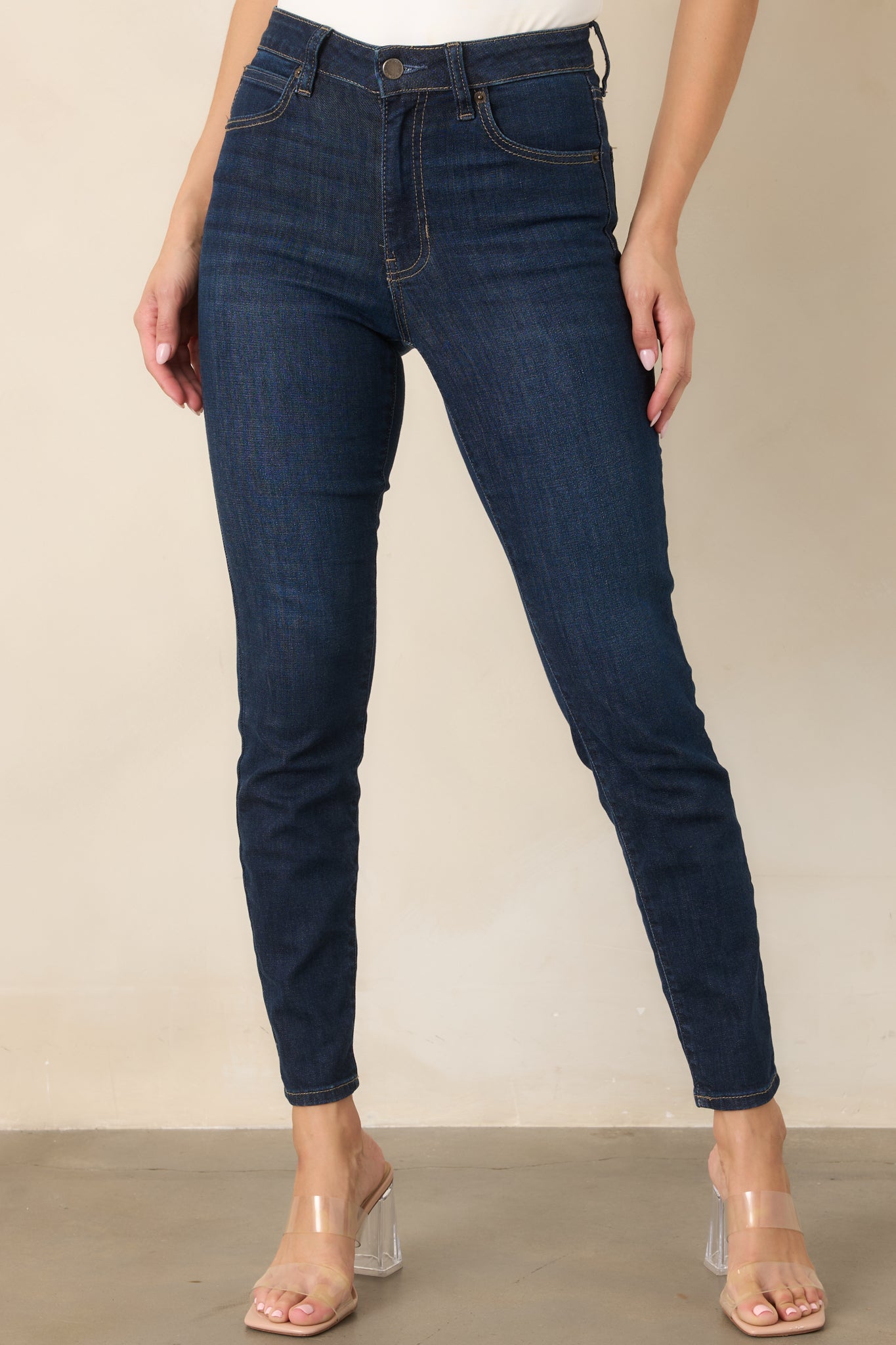 Detailed view of the dark denim showing the sleek skinny-leg construction and contrasting tan topstitching along the seams.