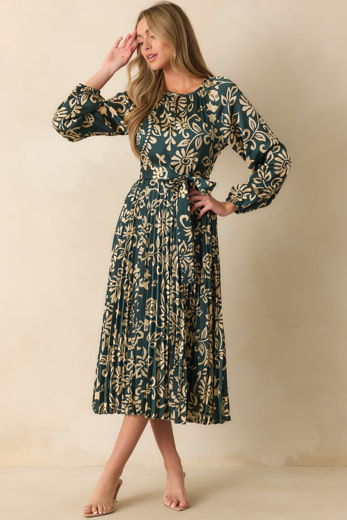 Dark teal dress styled with a pleated skirt and beige floral print throughout.