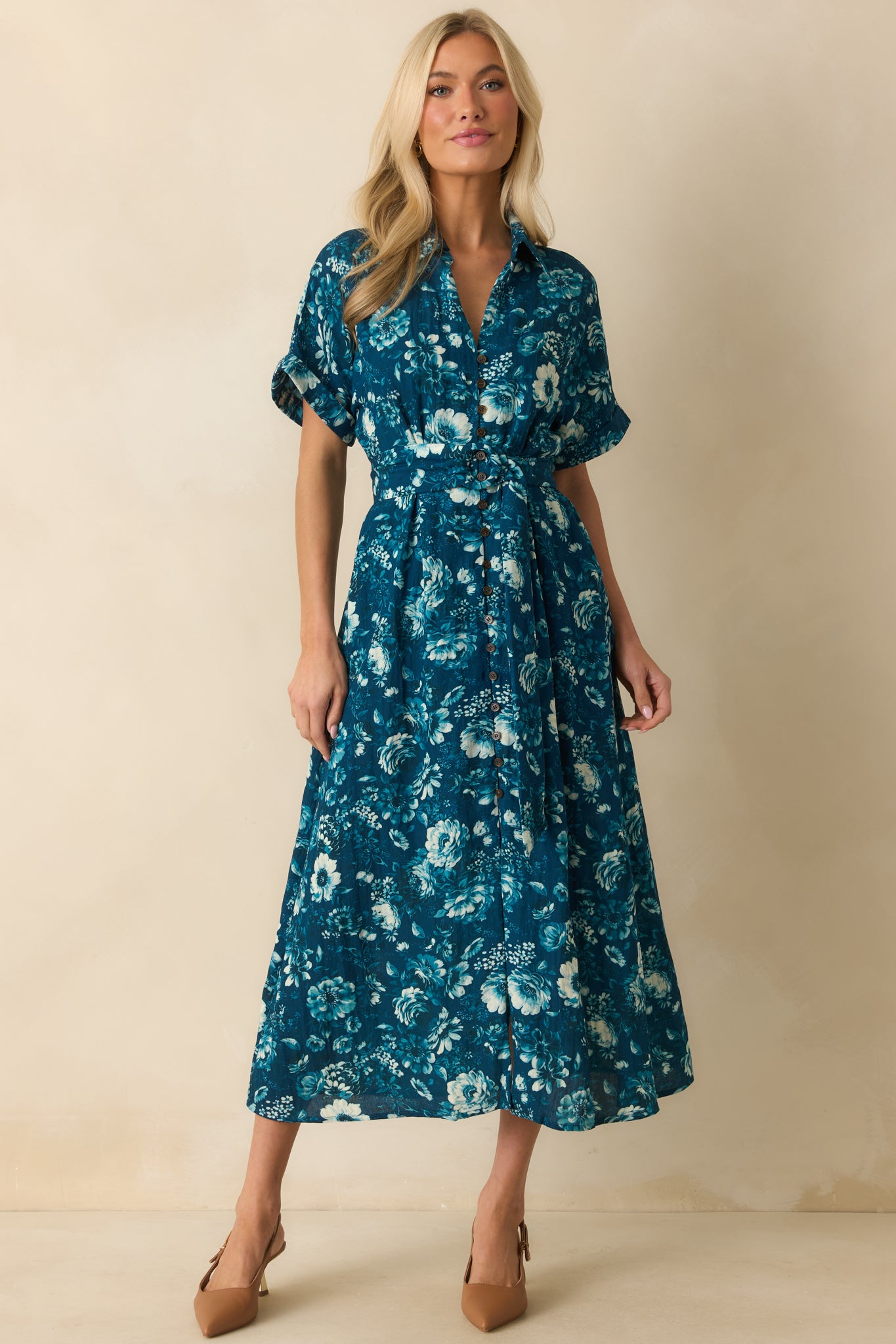 Button-front floral dress in dark teal with functional pockets, short cuffed sleeves, and subtle blue and green floral details.