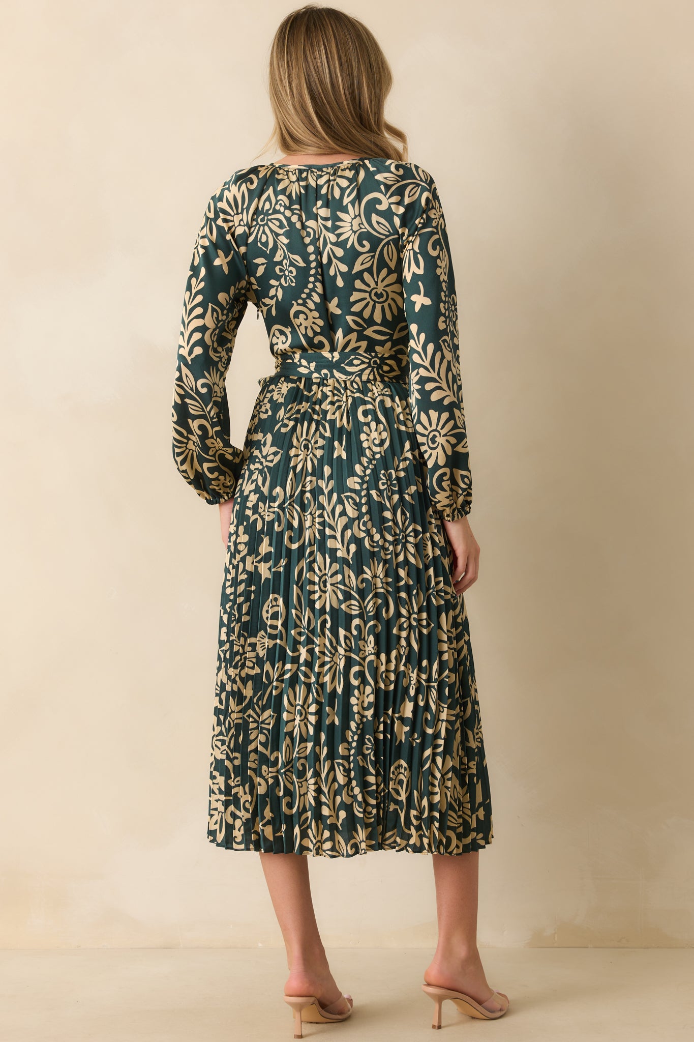 Rear view of the dark teal floral dress with long sleeves and waist tie belt.