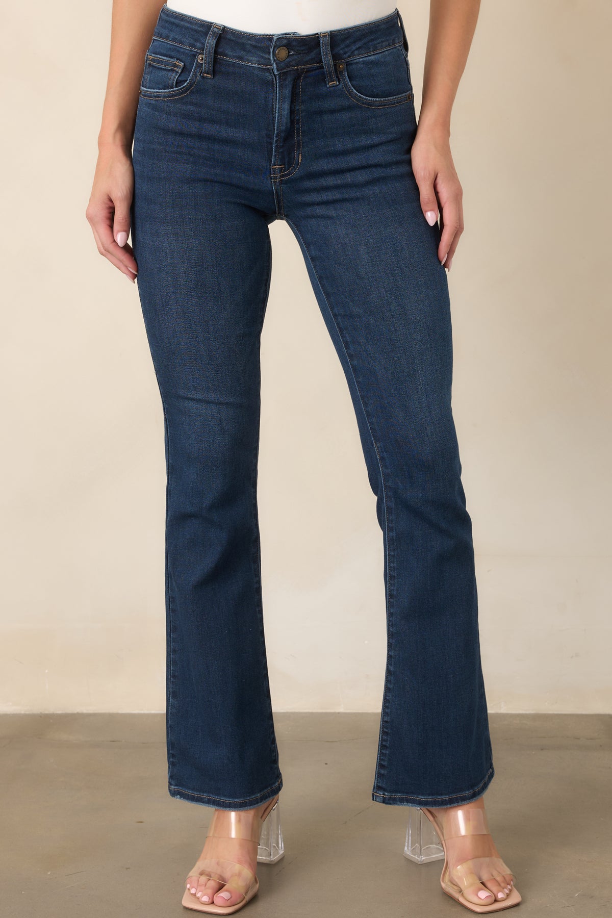 Dark-wash flare jeans emphasizing the gradual leg opening below the knee and cleanly finished denim hem.