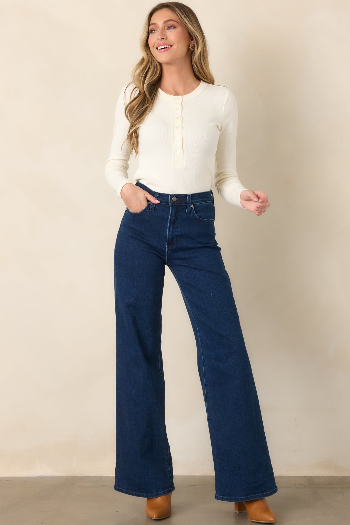Dark wash jeans with a high-rise waist, classic button and zipper closure, functional front pockets, back pockets, and a wide-leg silhouette.