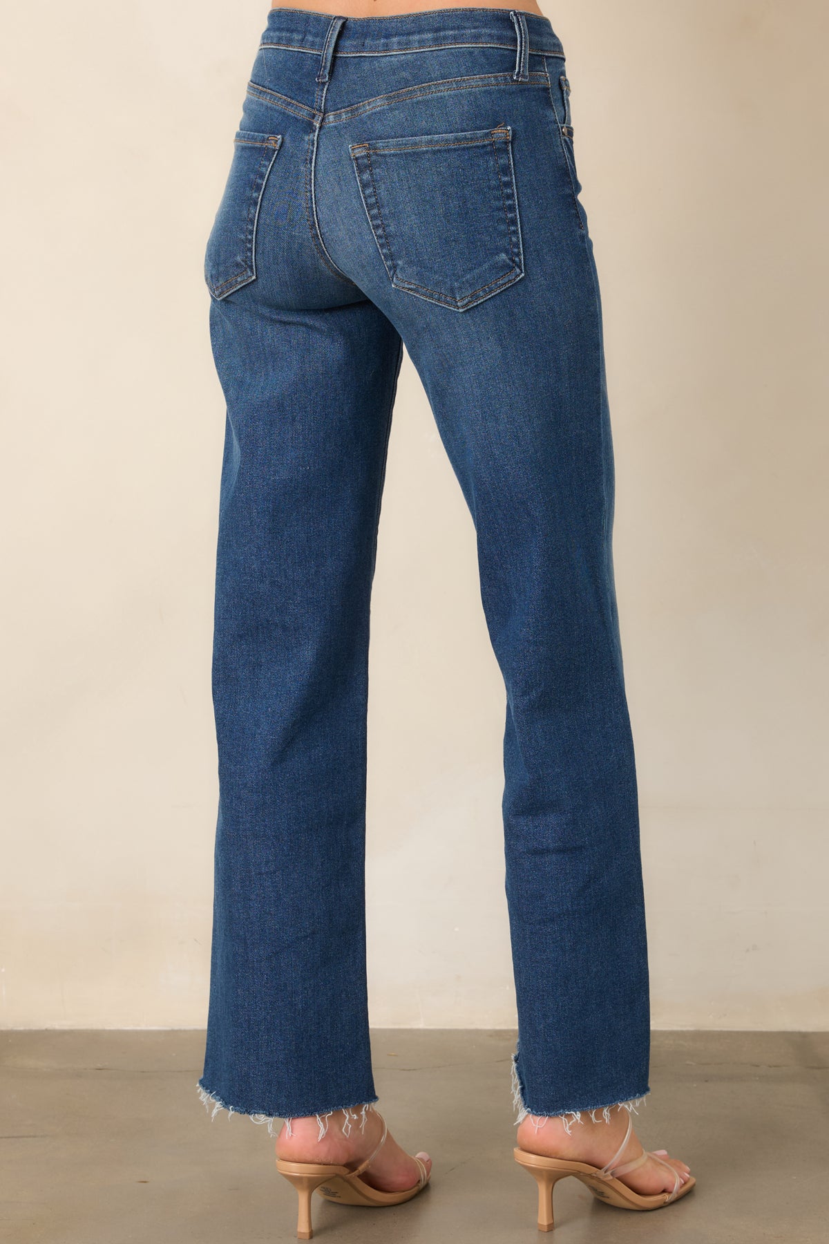 Rear of the dark wash jeans showing the high waist, straight-leg cut, belt loops, and functional back pockets.