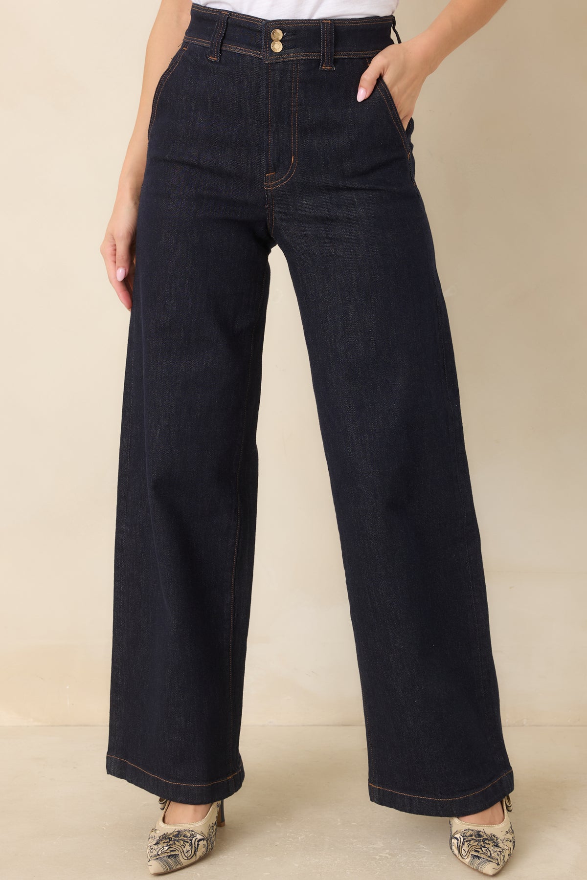 Dark wash wide leg jeans featuring a high-rise waistband with double gold-tone buttons, slanted pockets, and contrast stitching.